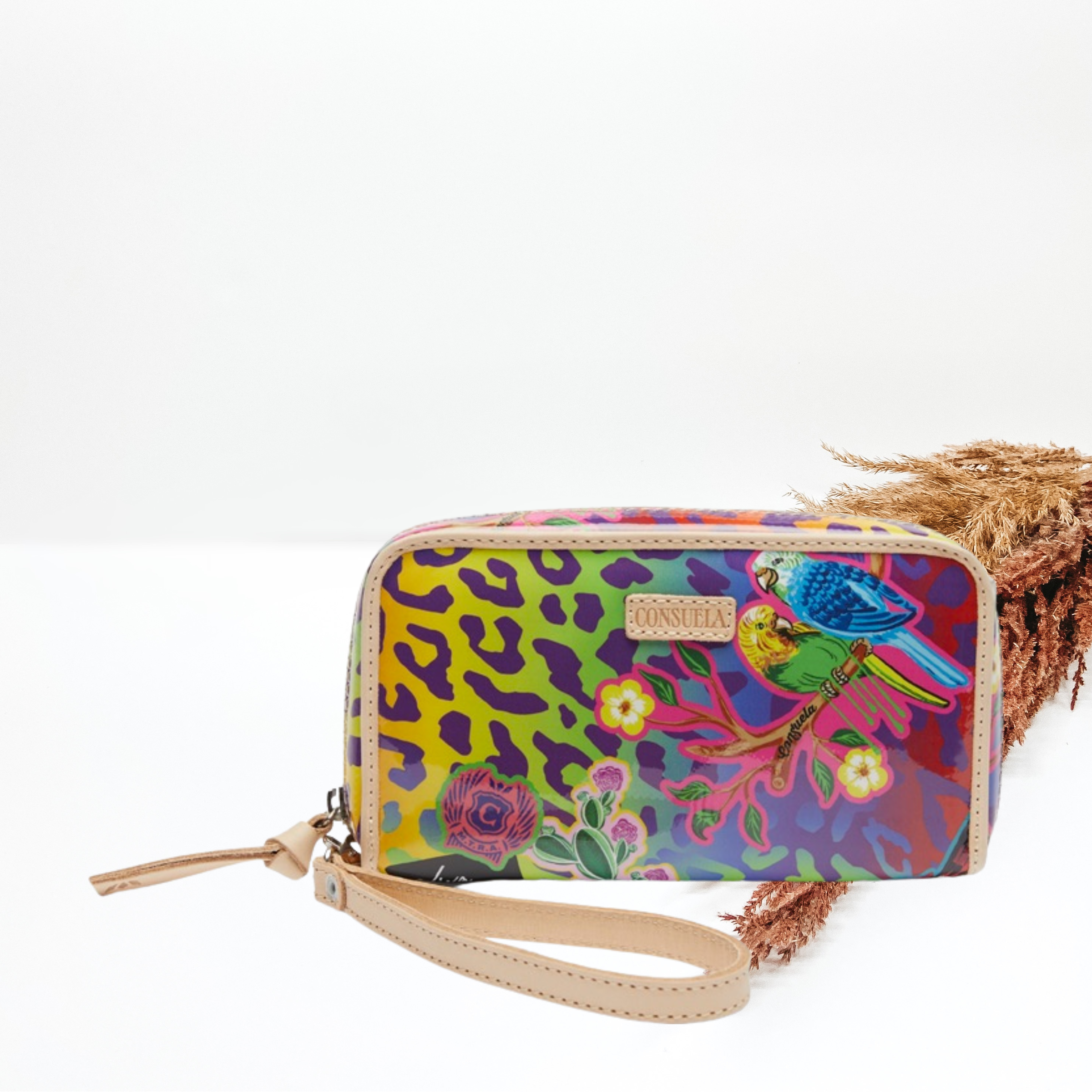 In the middle of the picture is a wristlet wallet in a rainbow leopard with different designs including a parrot and flowers. Background is white. 