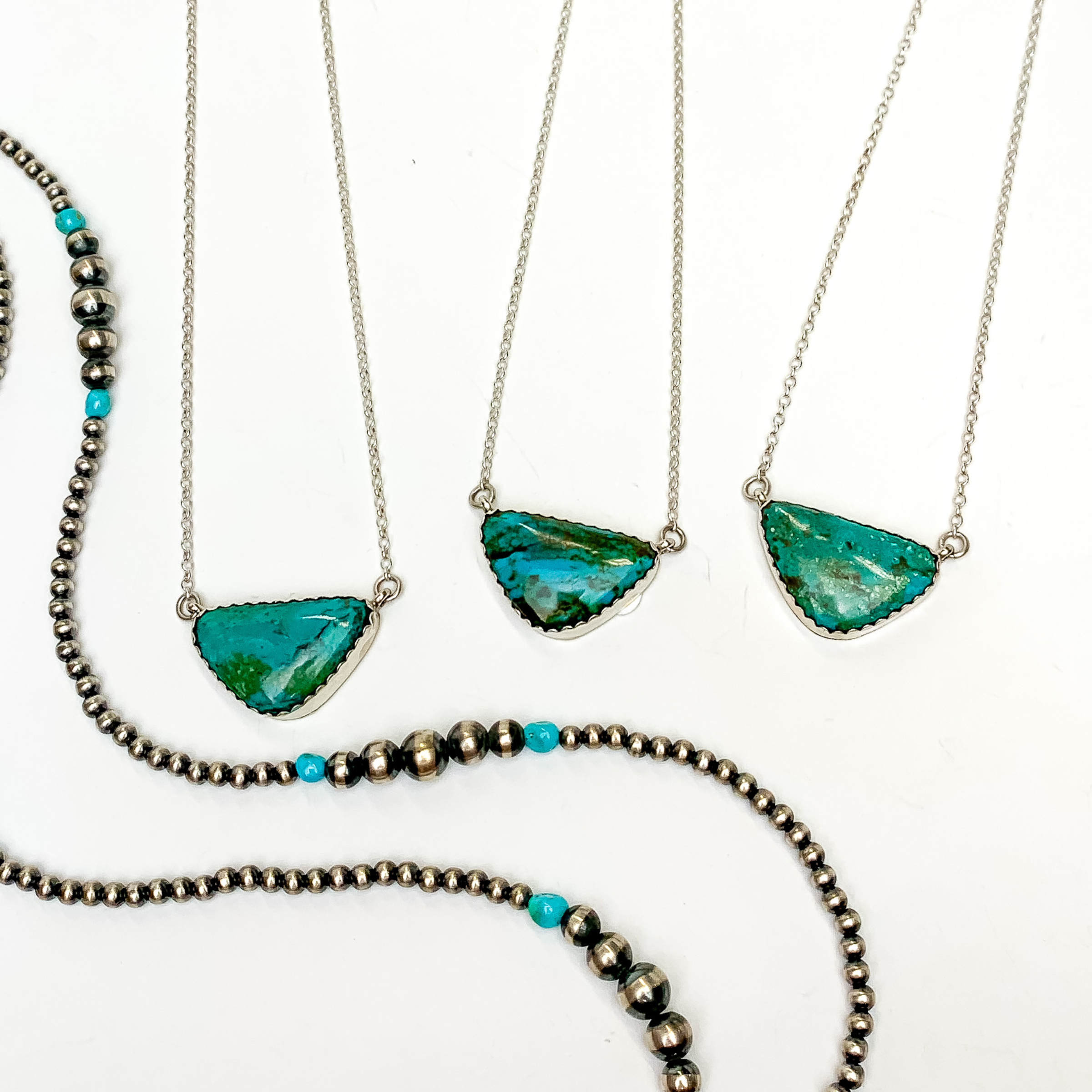 Three silver chain necklaces with triangle stone pendant in turquoise. These necklaces are pictured on a white background with silver beads.