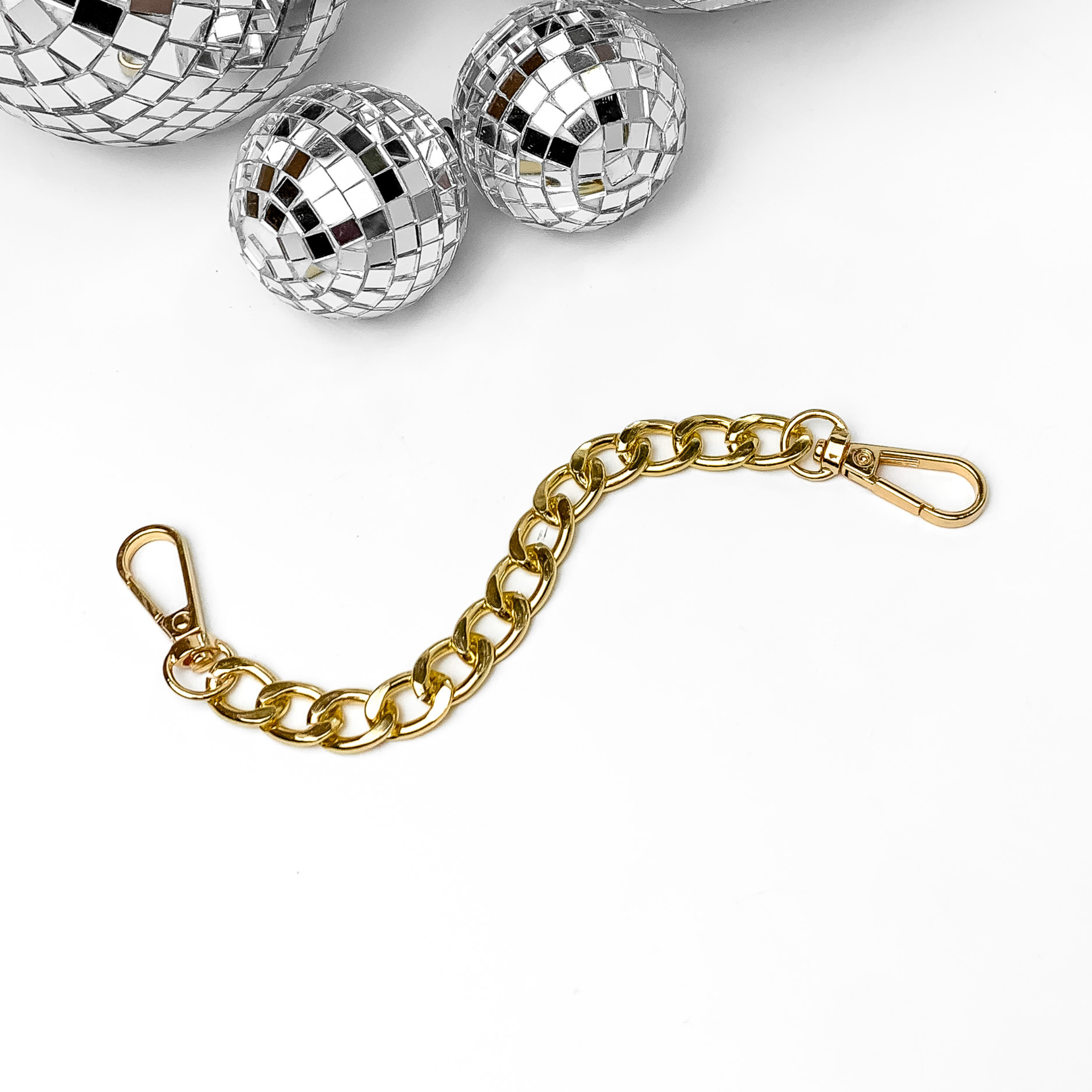 Gold chain with clasps on each end. thi chain is pictured on a white background with disco balls at the top of the picture. 