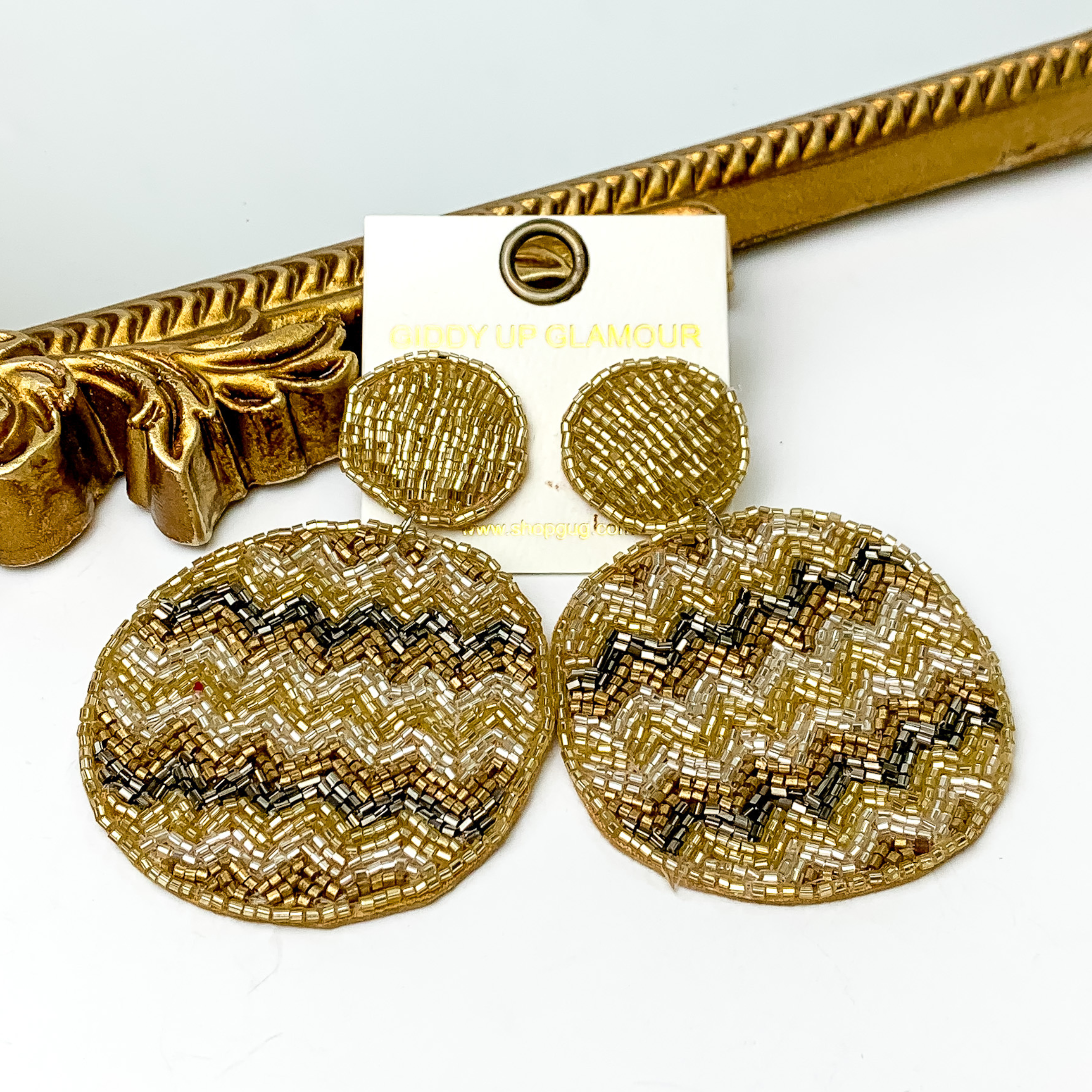 These are circle post back, gold beaded earrings with a beaded circle drop. These earrings include a chevron pattern with gold beads, silver beads, and light gold beads. These earrings are pictured in front of a gold mirror on a white background. 