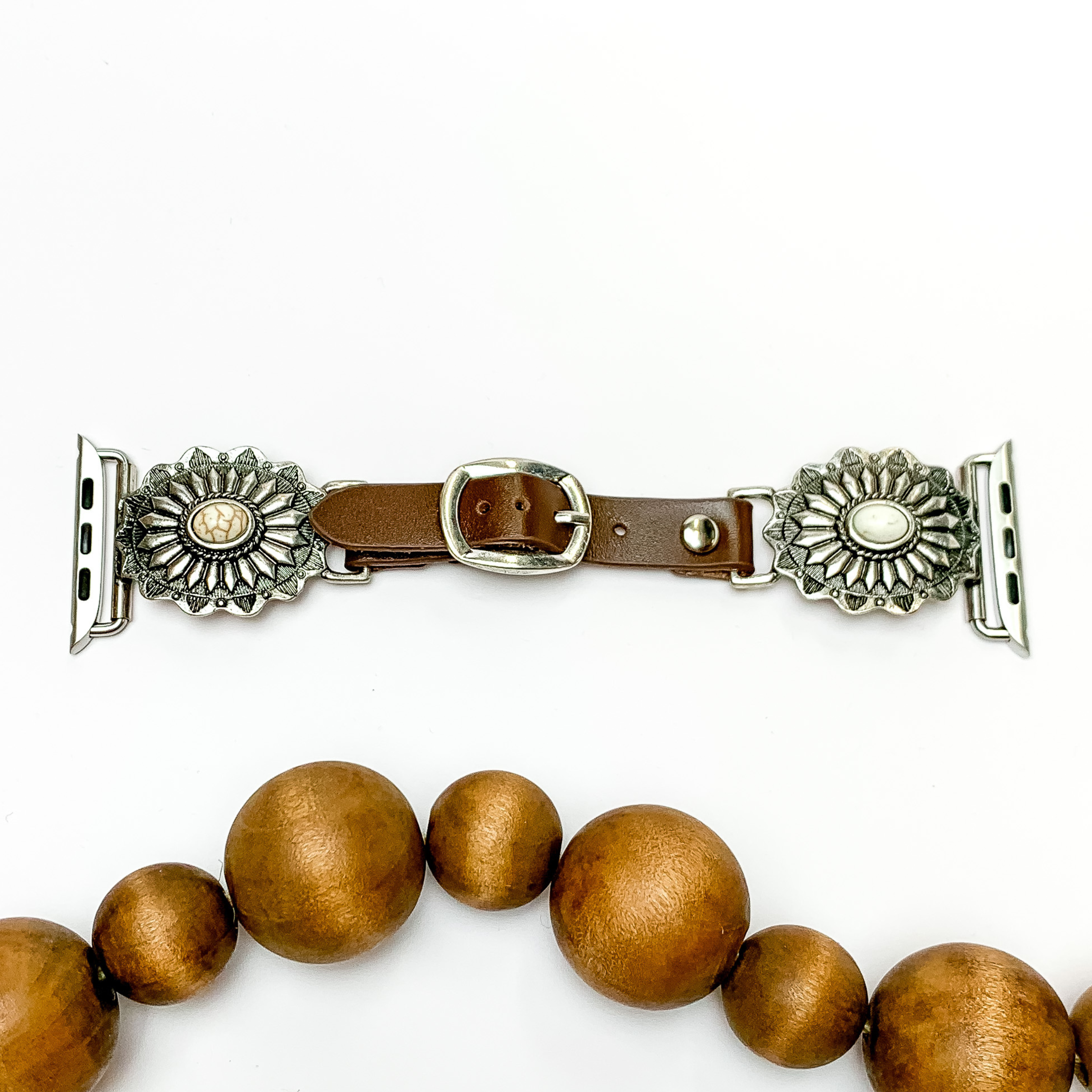 Dark Brown watch band with silver, oval concho pendants and Apple watch band acessories. The pendants include rows a center ivory stone. This watch band is pictured on a white background with brown beads below the band. 