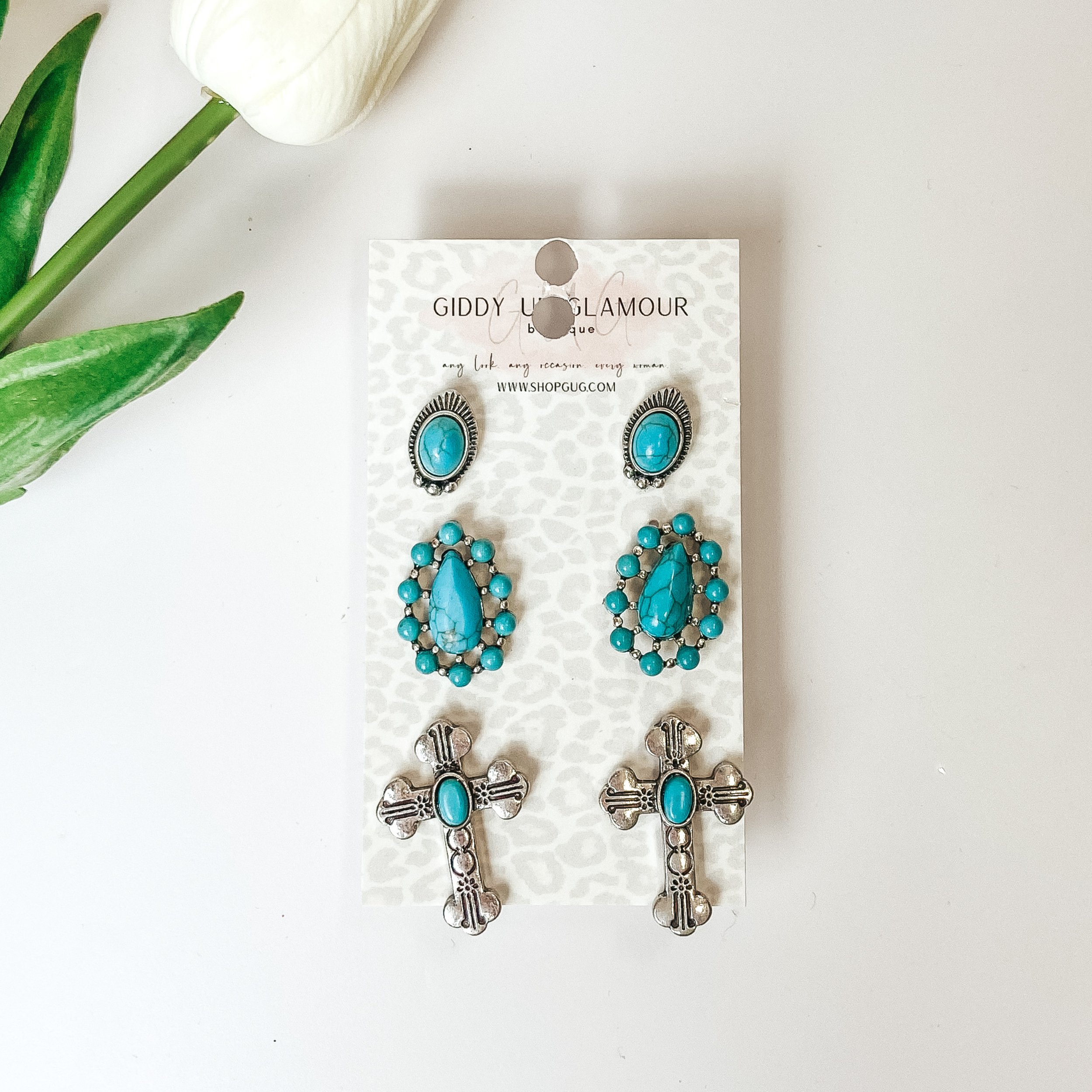Three multi pack of silver and turquoise stud earrings. On a white background with a flower in the top left