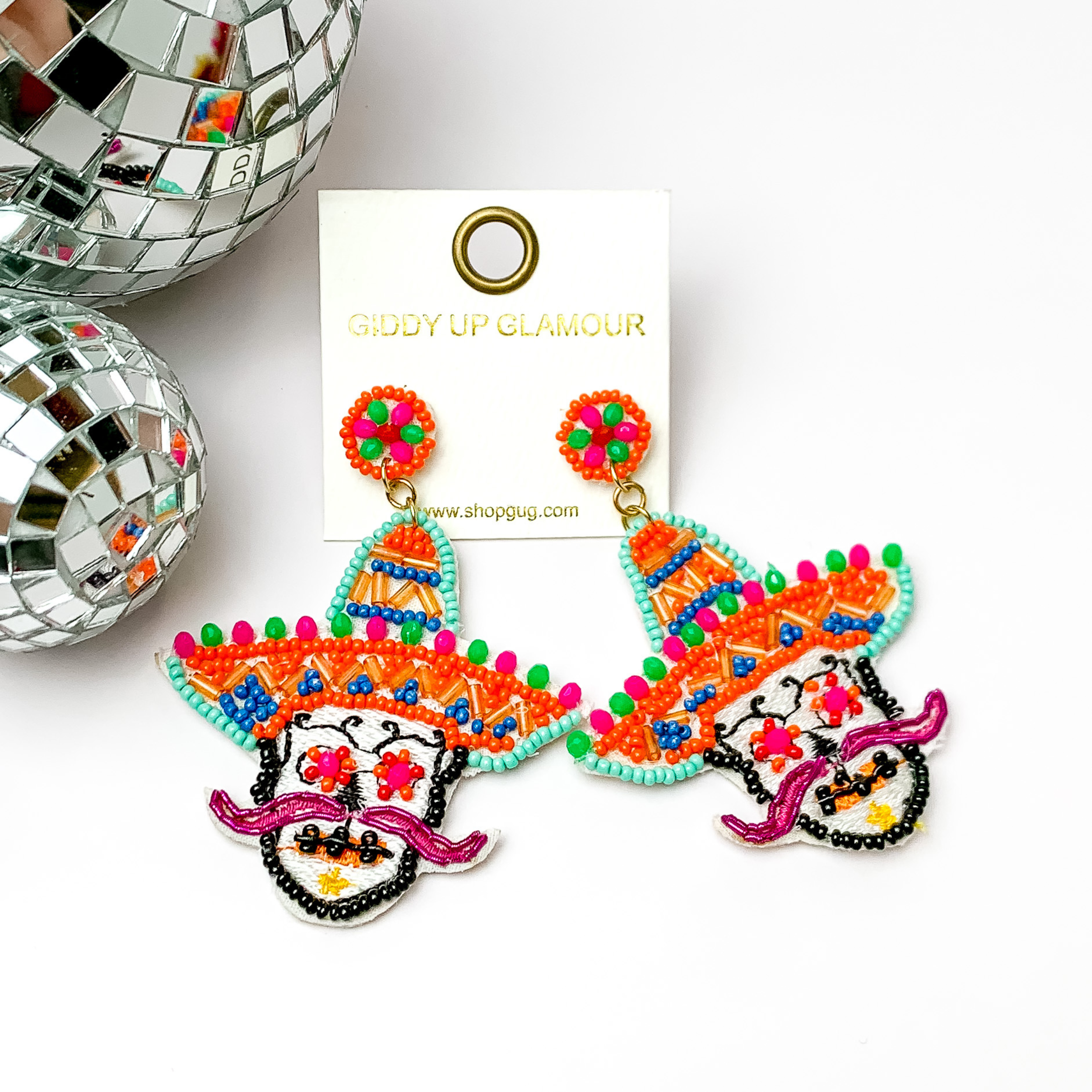These are sugar skull post earrings in orange and other colors.. The rest has multicolored stitching all around. These earrings are taken on a white background with disco balls in the left.