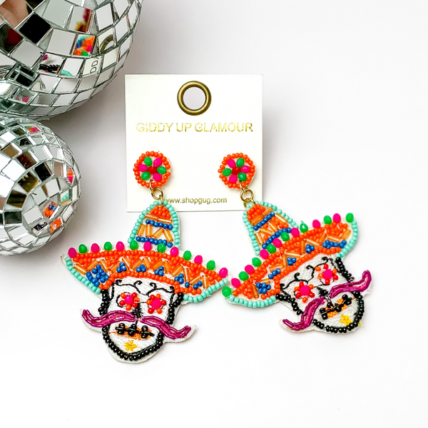 These are sugar skull post earrings in orange and other colors.. The rest has multicolored stitching all around. These earrings are taken on a white background with disco balls in the left.
