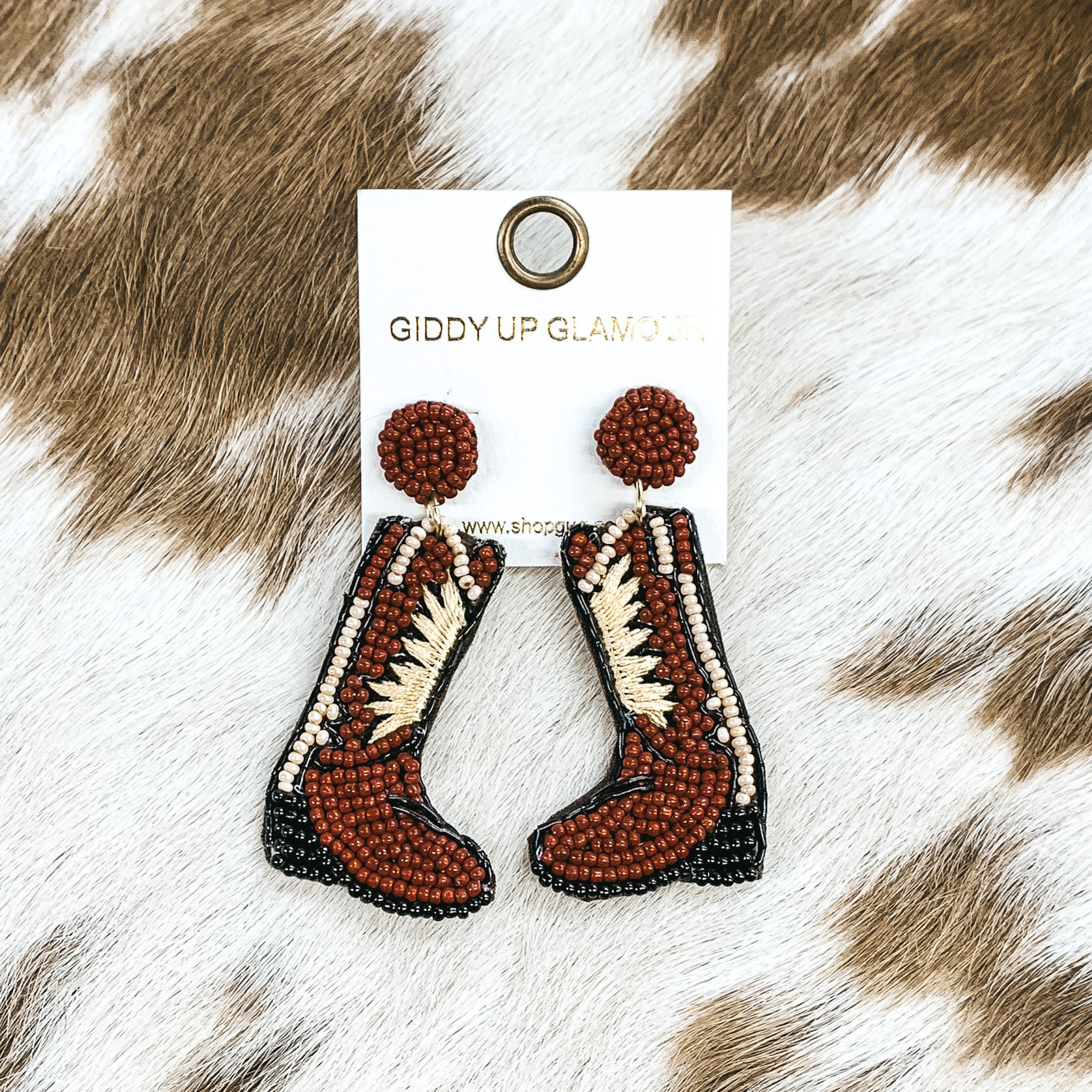 Beaded brown boot post back earrings. These earrings include black and ivory detailing. These earrings are pictured on a white and brown bow print hide material. 