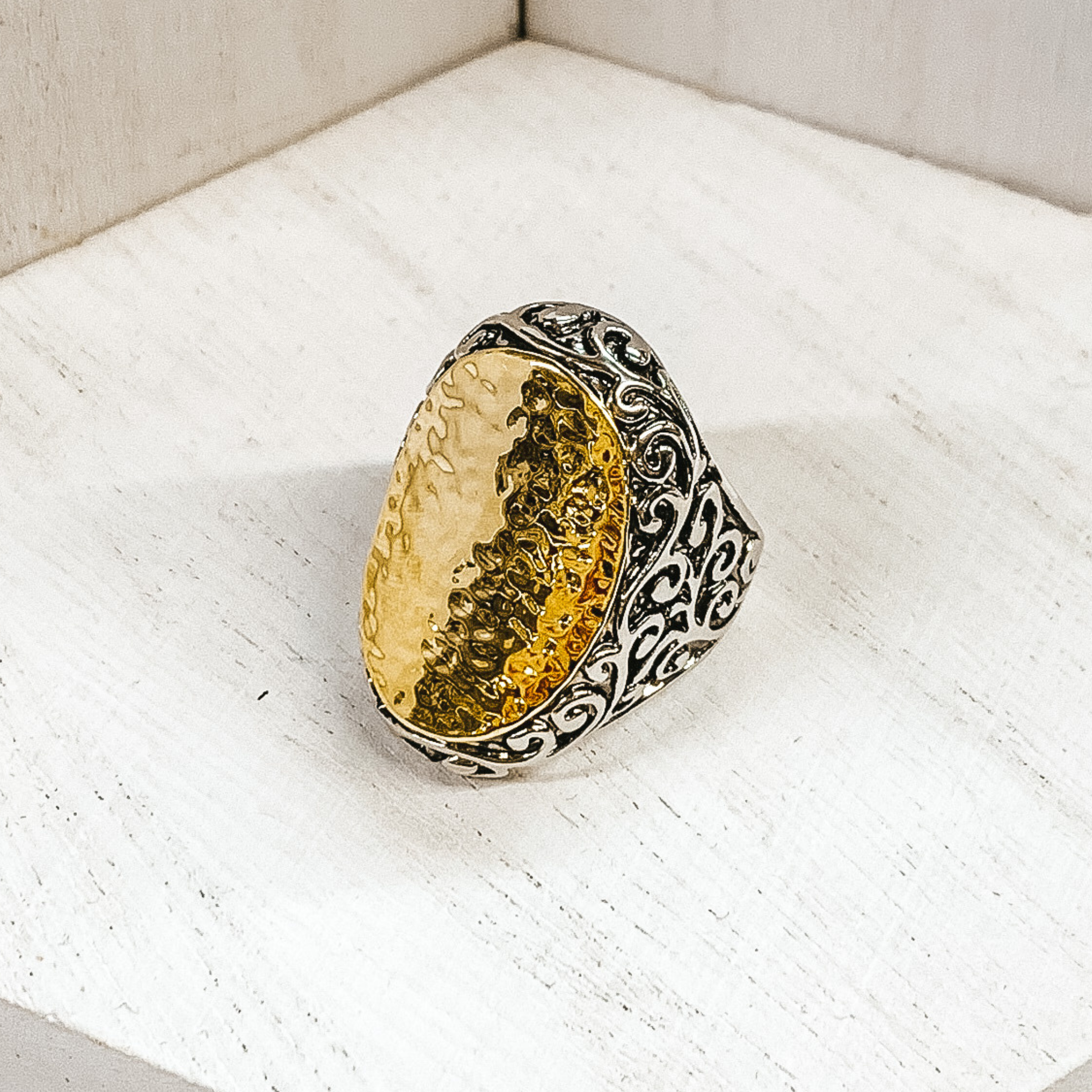 Large, silver engraved ring with a gold, hammered oval pendant in the center. This ring is pictured on a white background. 