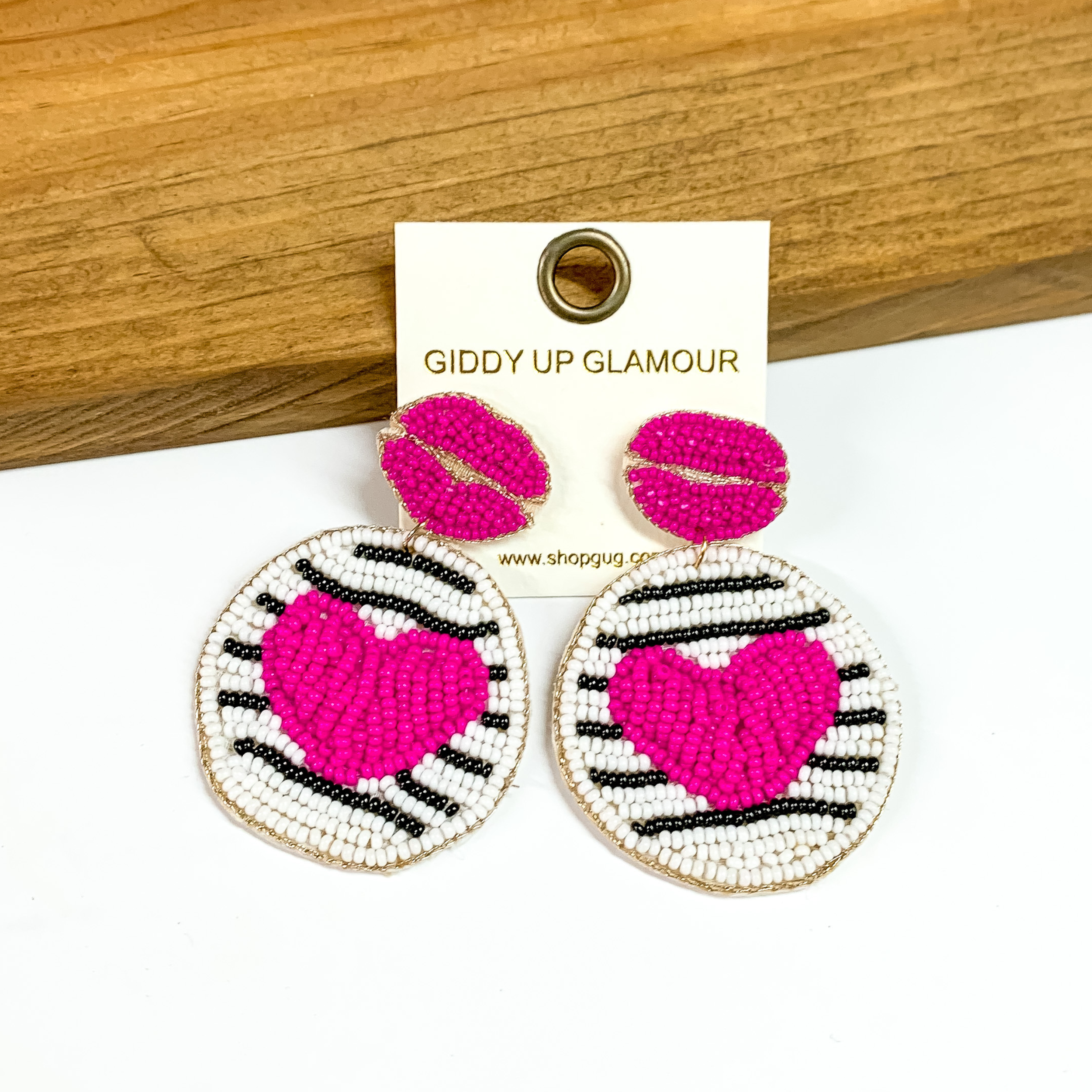 The cutest heart and lips seedbead earrings with post backs. The posts are hot pink lips made from seedbeads and the bottom part of the earring is white and black stripe with hot pink hearts in the middle. The earrings are perfect for Valentine's Day. The earrings are placed on a white and wood background.