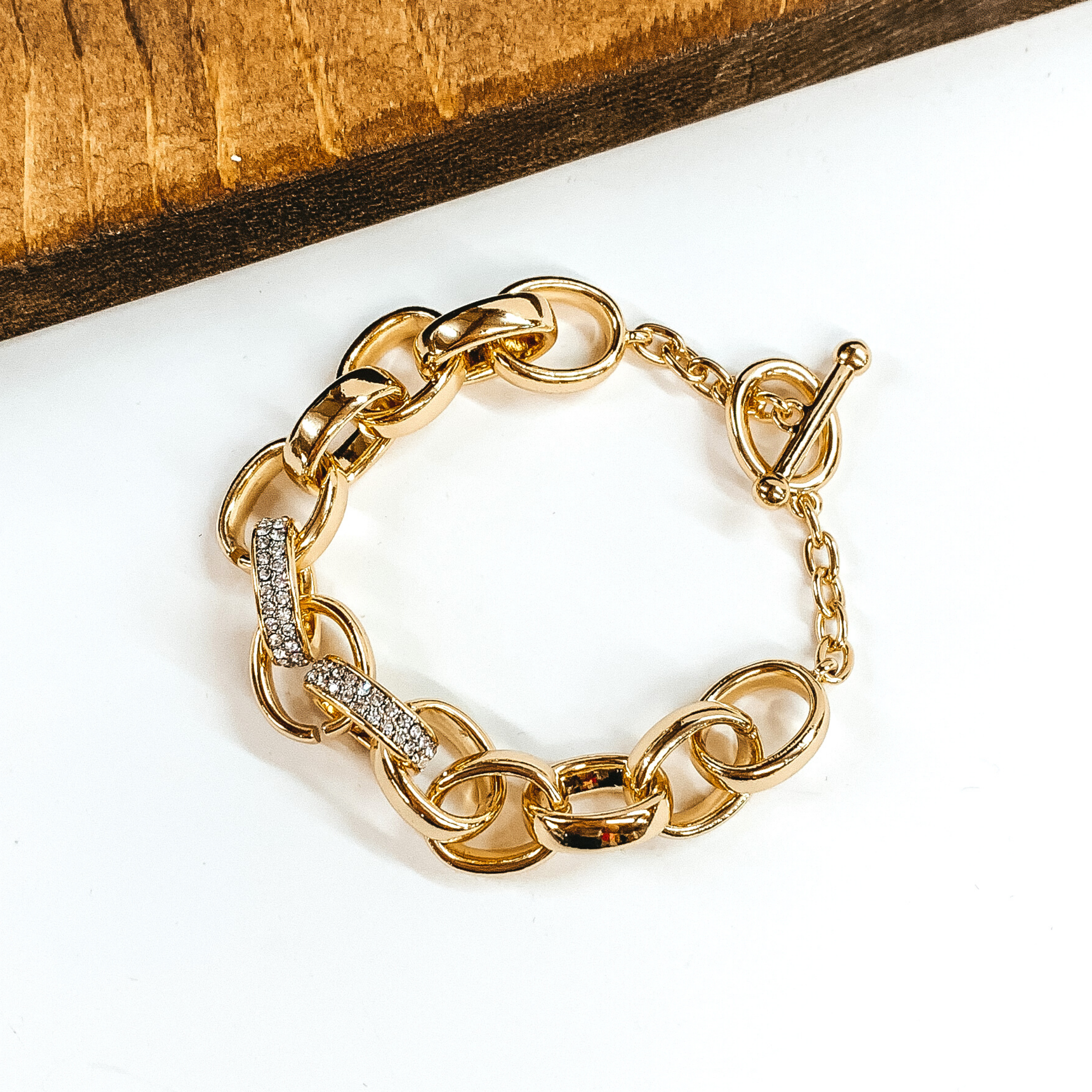 Thick, gold chained bracelet with two chains covered in clear crystals. This bracelet has a toggle clasp. This bracelet is pictured on a white background.