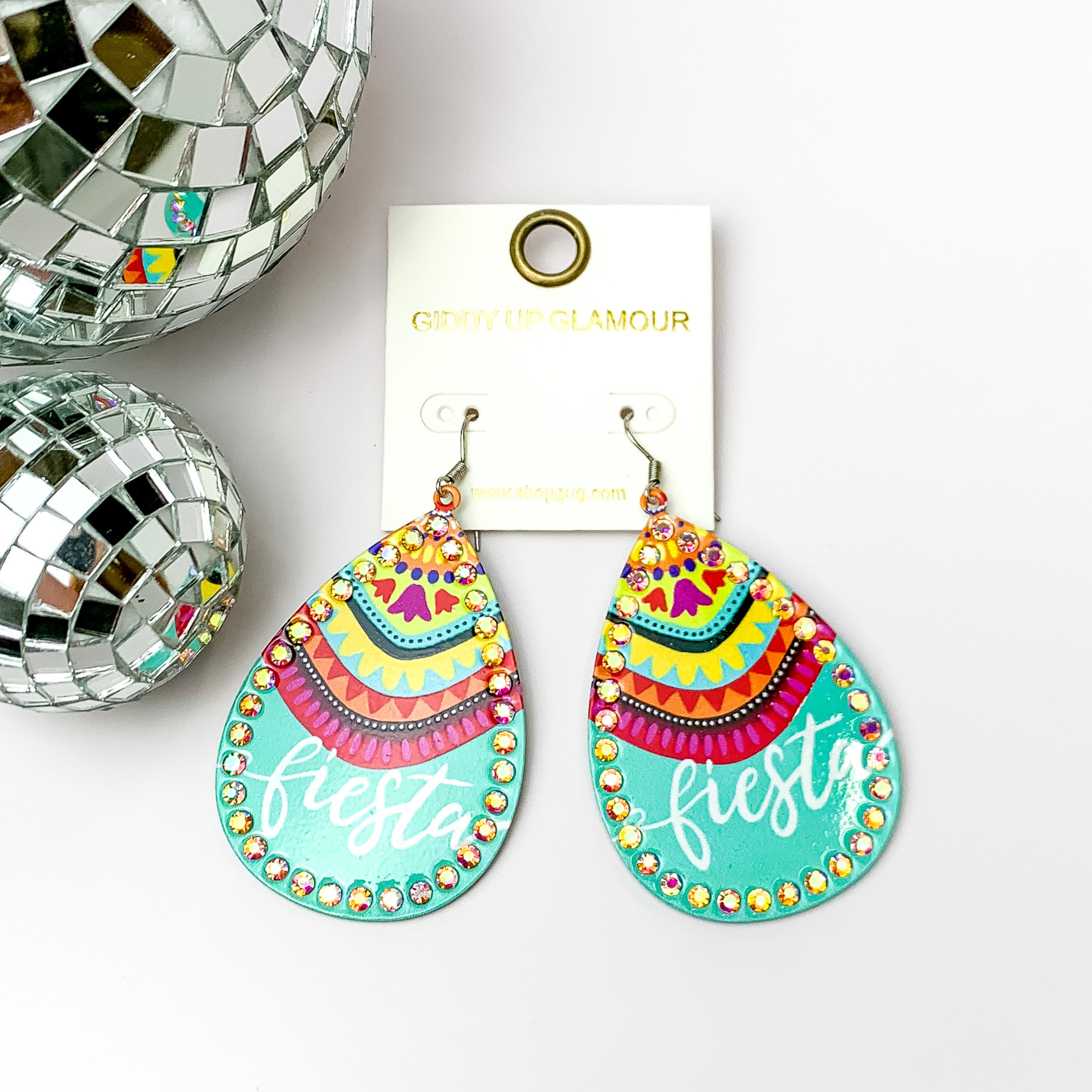  Pictured are teardrop metal turquoise earrings with ab crydtals around it. They are pictured with disco balls in the left corner on a white background.