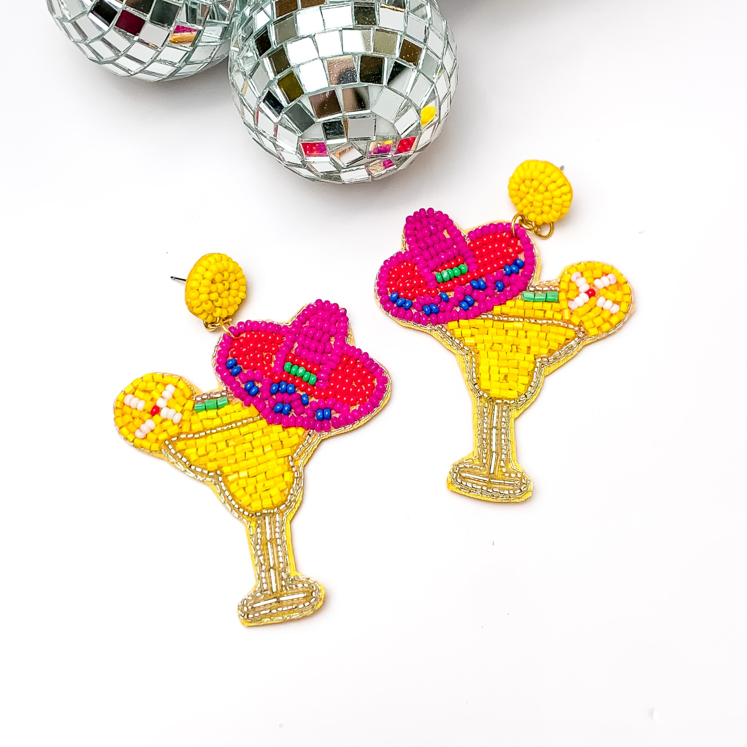 Margarita sombrero seed beaded drop earrings in yellow. The sombrero has orange, dark blue, and pink sequins. Taken in a white background with disco balls in the left corner.