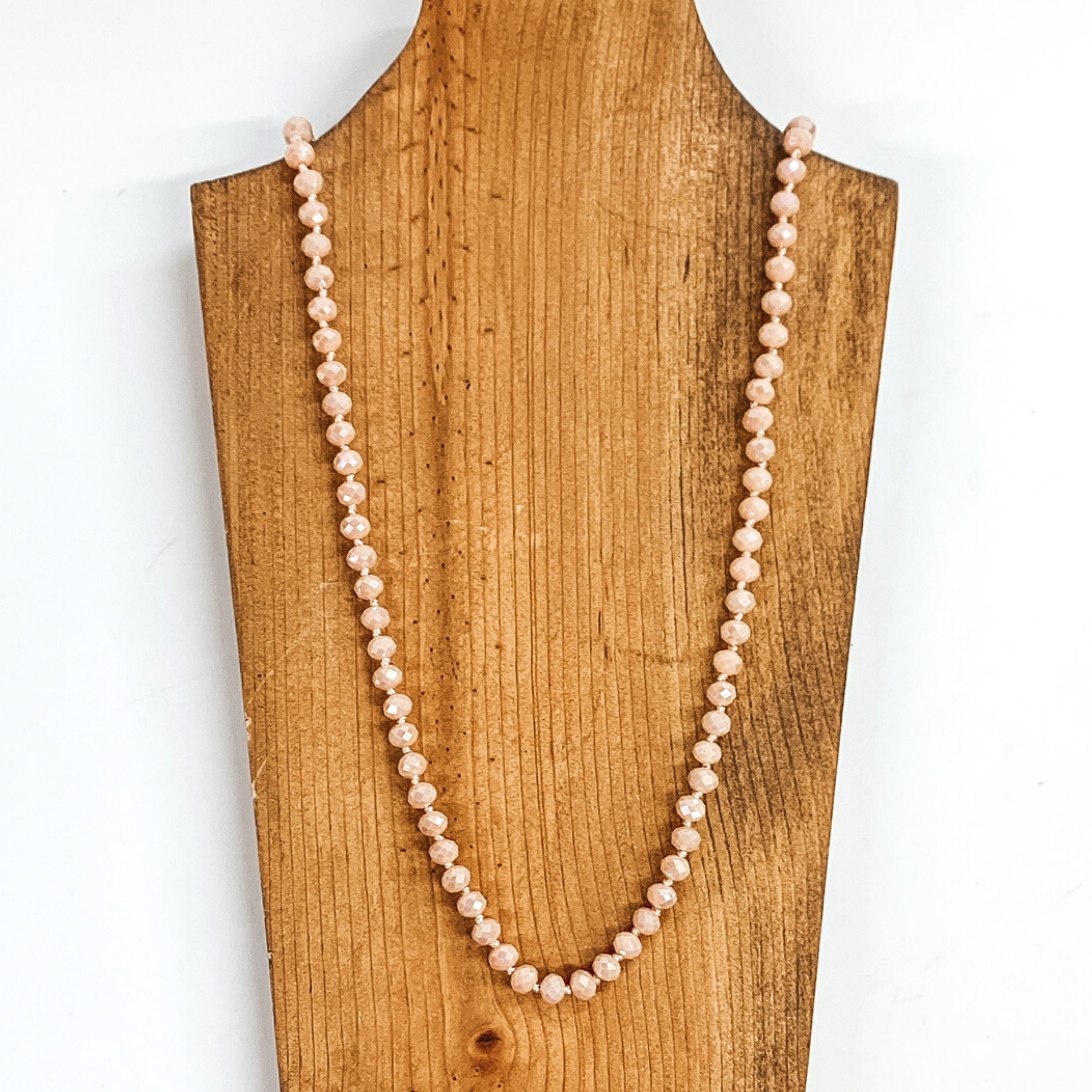 Blush pink crystal beaded necklace. This necklace is pictured on a brown necklace holder on a white background. 
