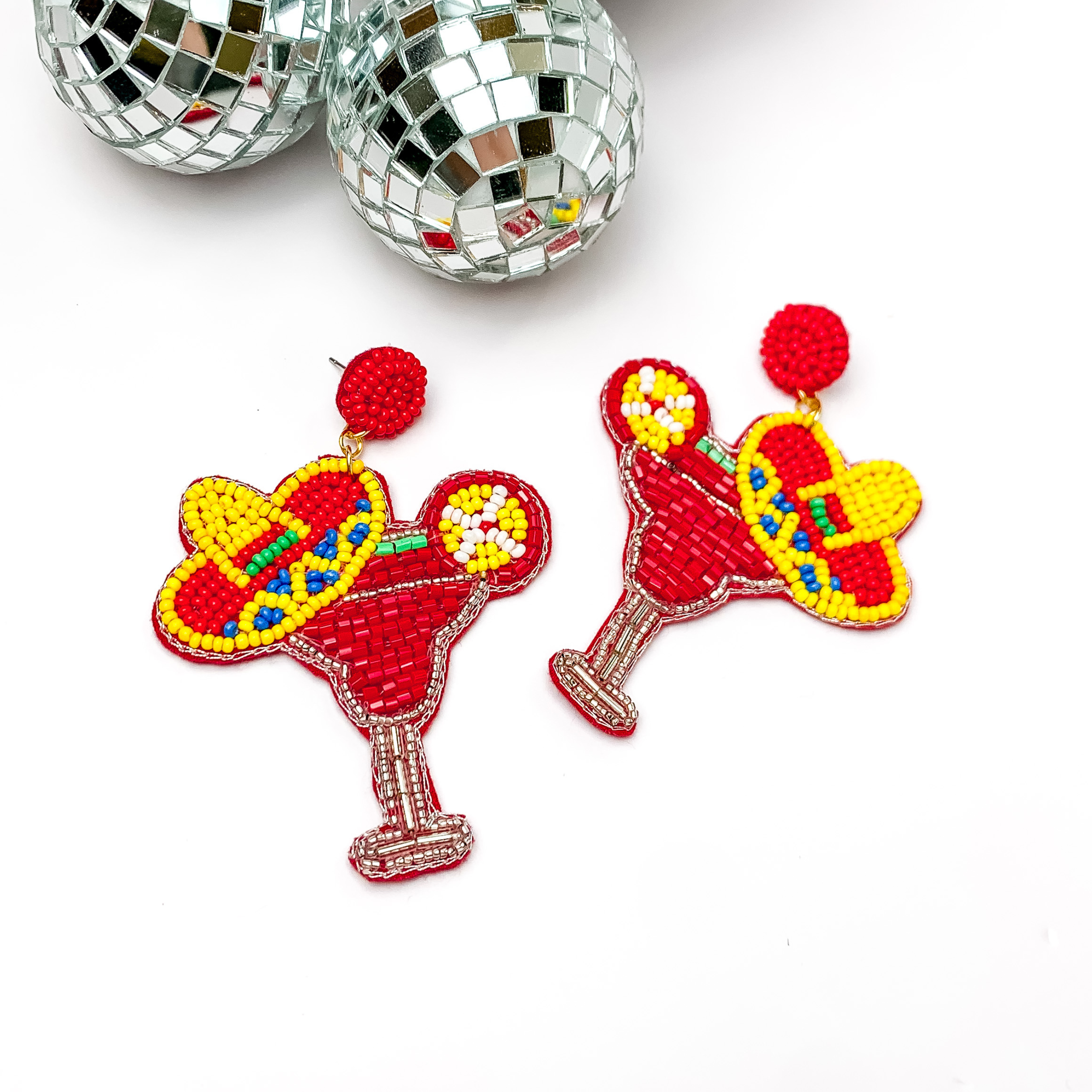 Margarita sombrero seed beaded drop earrings in red. The sombrero has yellow, dark blue, and red sequins. Taken in a white background with disco balls in the left corner.