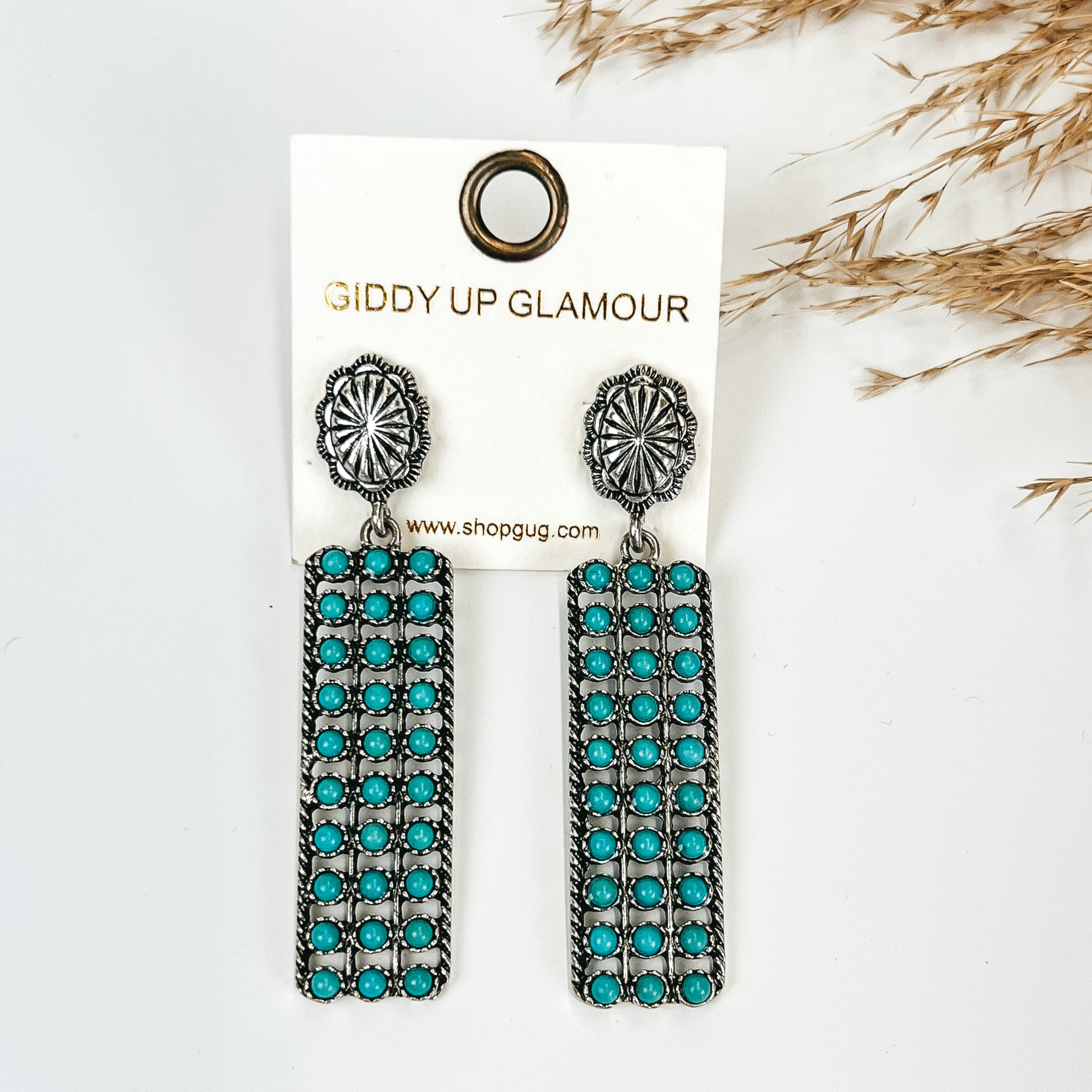 Silver Tone Concho Earrings with Turquoise Rectangle Drop, Pictured with Pampas grass on a white background.