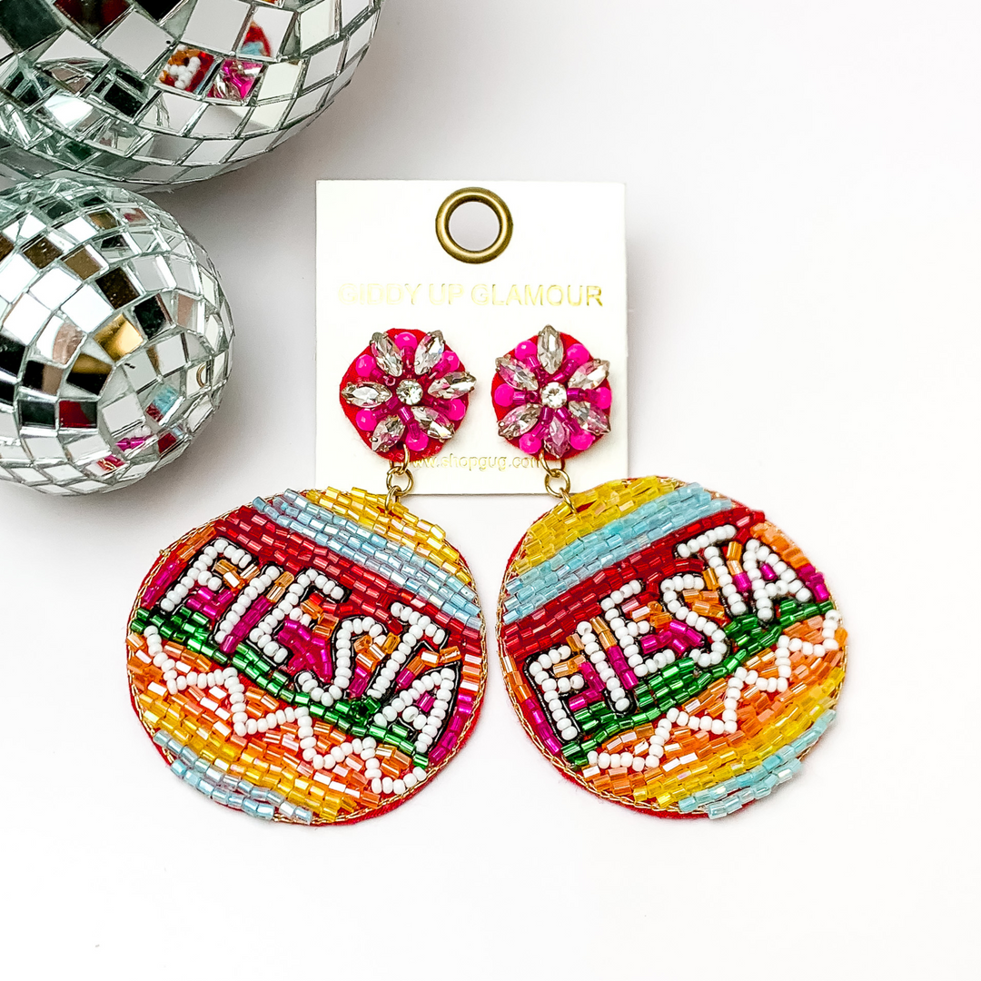 These are a multicolored beaded earrings with fiesta in white beads. There is also a clear crystal beads towards the top of the earrings. These earrings are pictured on a white background with disco balls in the left corner.
