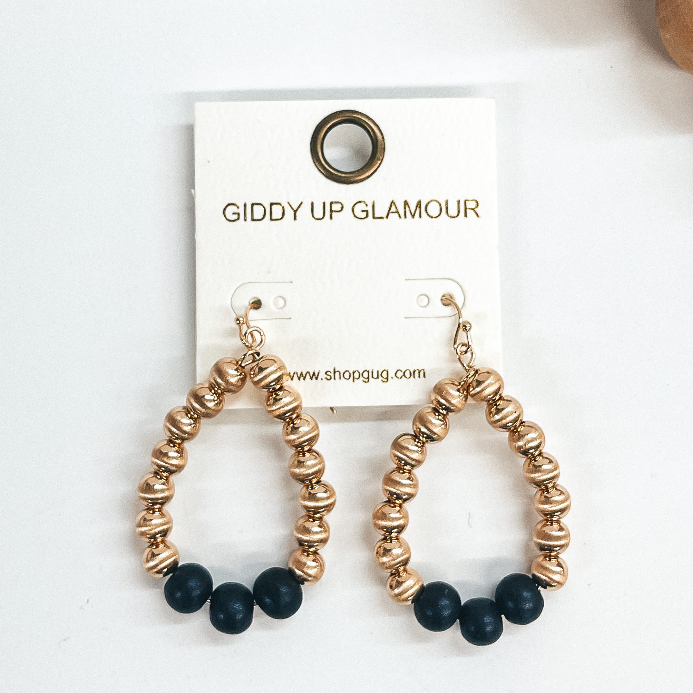 Gold big beaded teardrop earrings with three wood  beads in black. Taken on a white background.
