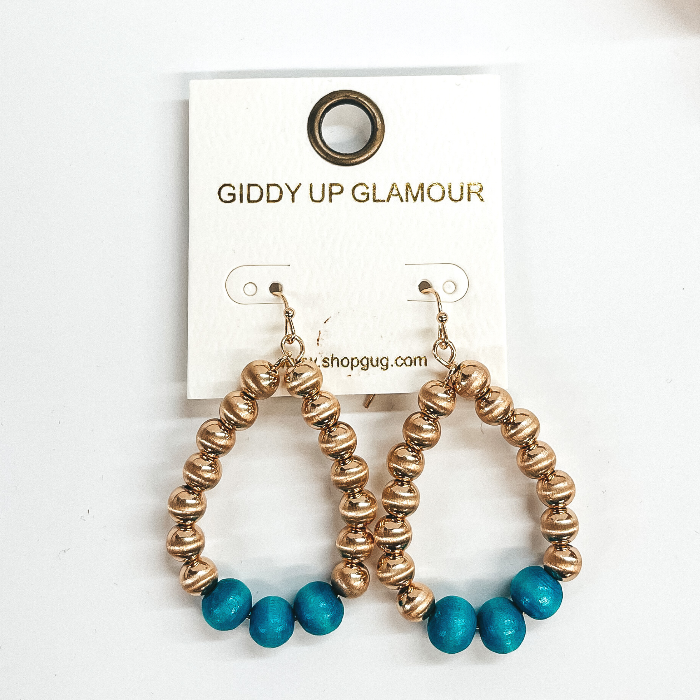 Gold big beaded teardrop earrings with three wood  beads in turquoise. Taken on a white background.