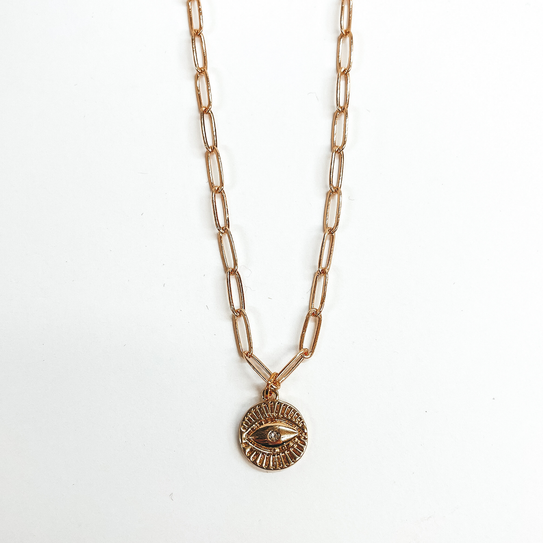 This is a gold paperclip chain necklace with a  gold evil eye pendant. This is taken on a white  background.