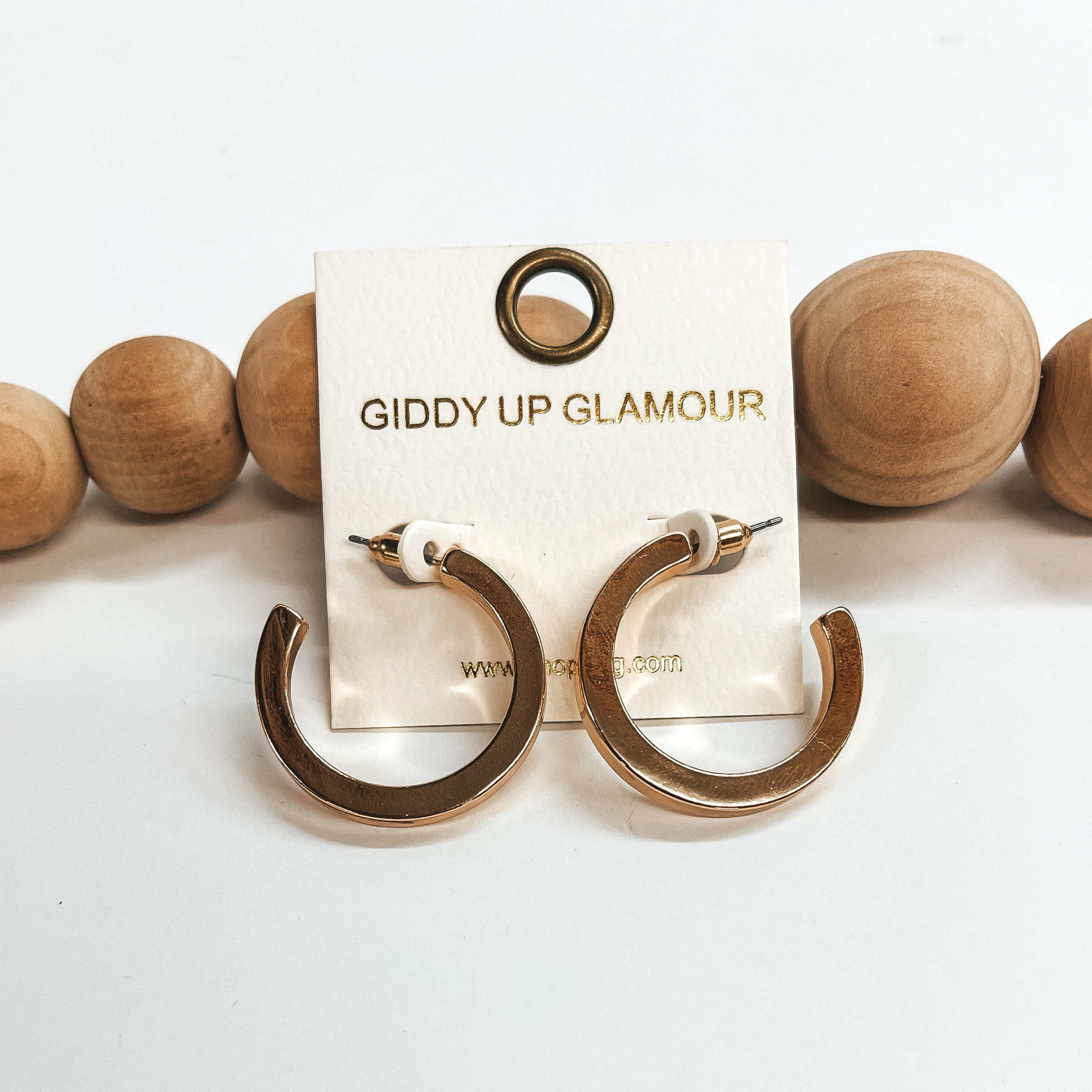 These are medium shiny gold hoops with a post back  backing. Taken on a white background and leaned up  against brown wood balls.