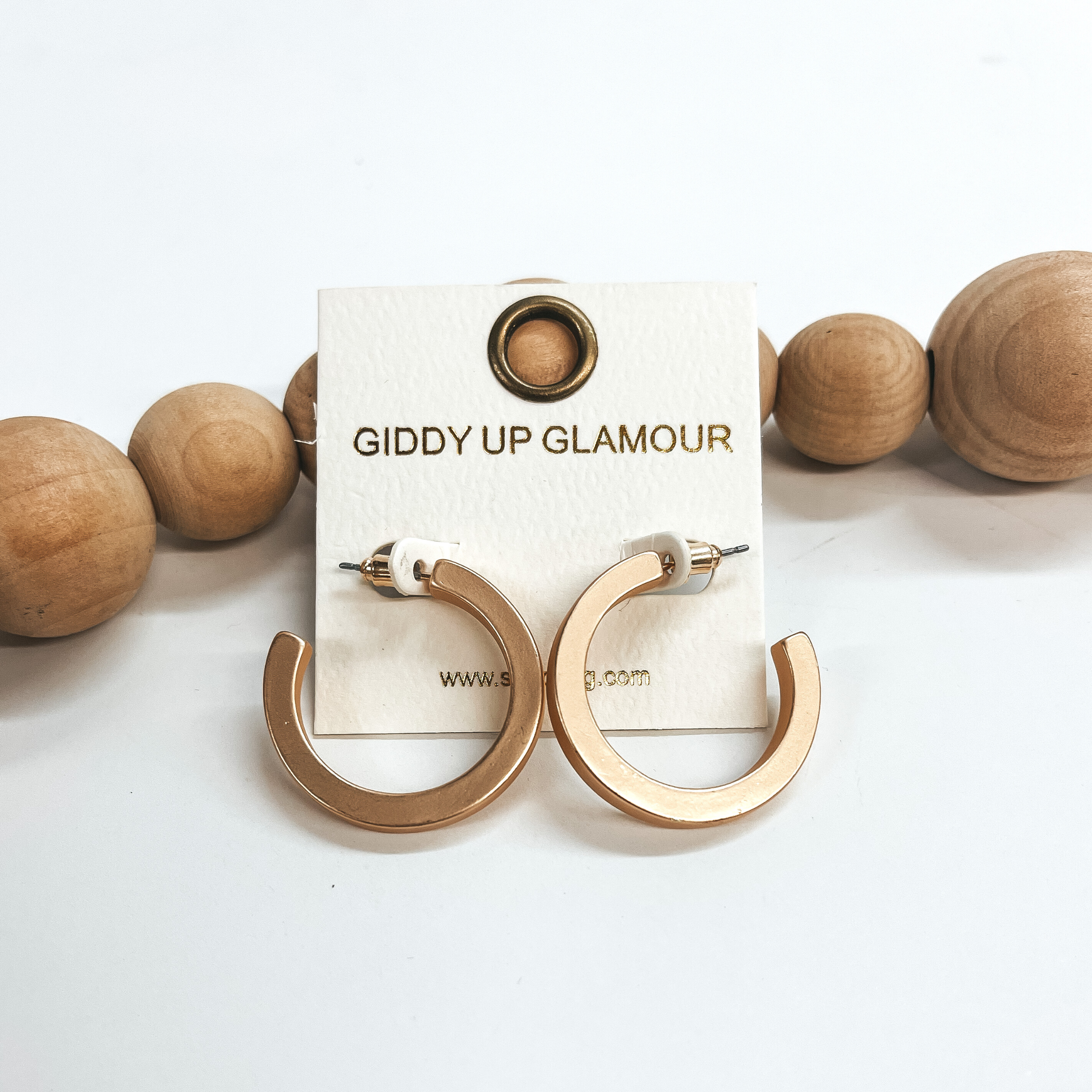 These are medium matte gold hoops with a post back  backing. Taken on a white background and leaned up  against brown wood balls.