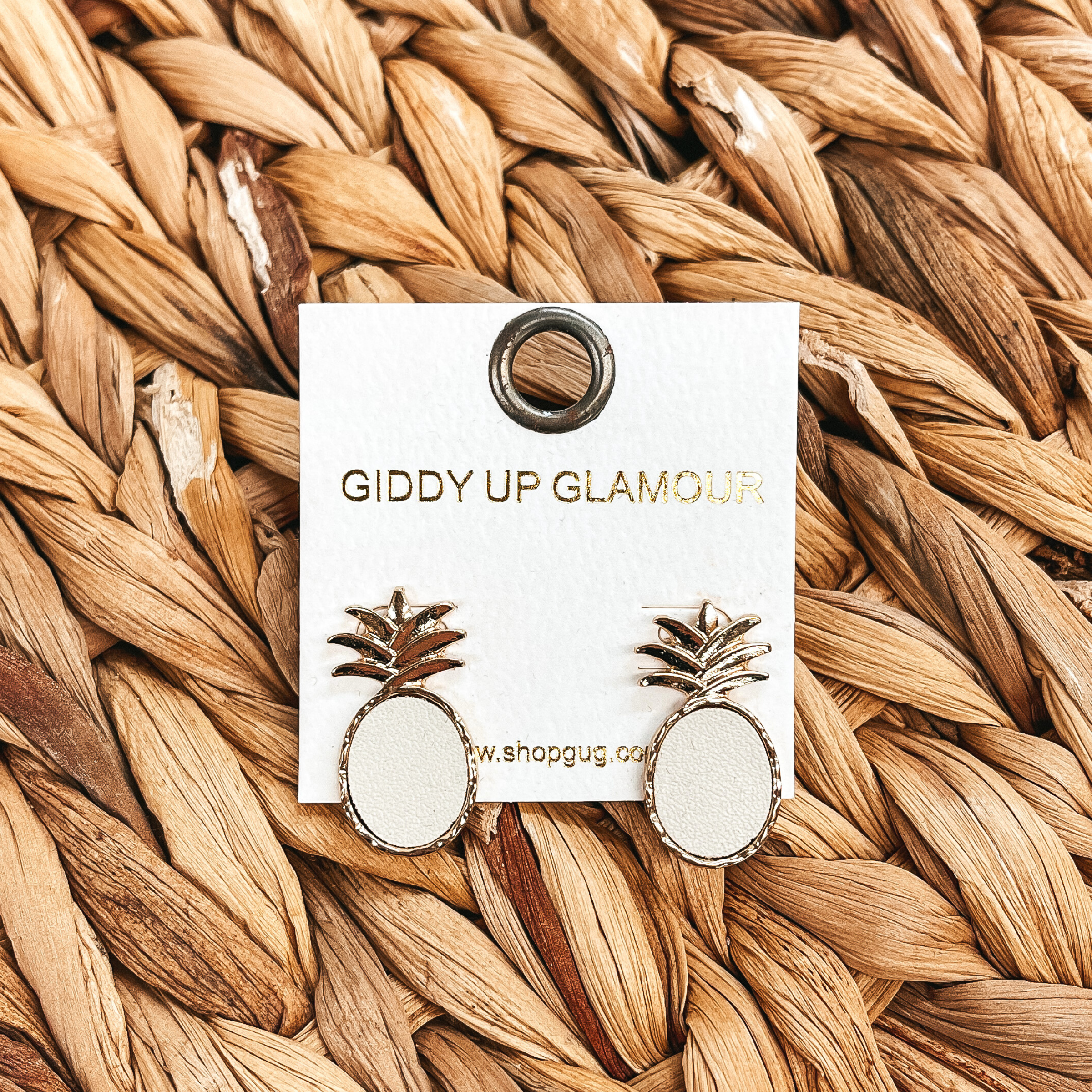 These are gold and ivory pineapple post back  earrings, the ivory is faux leather and it's in  a gold setting. These earrings are taken on a brown  woven plate.