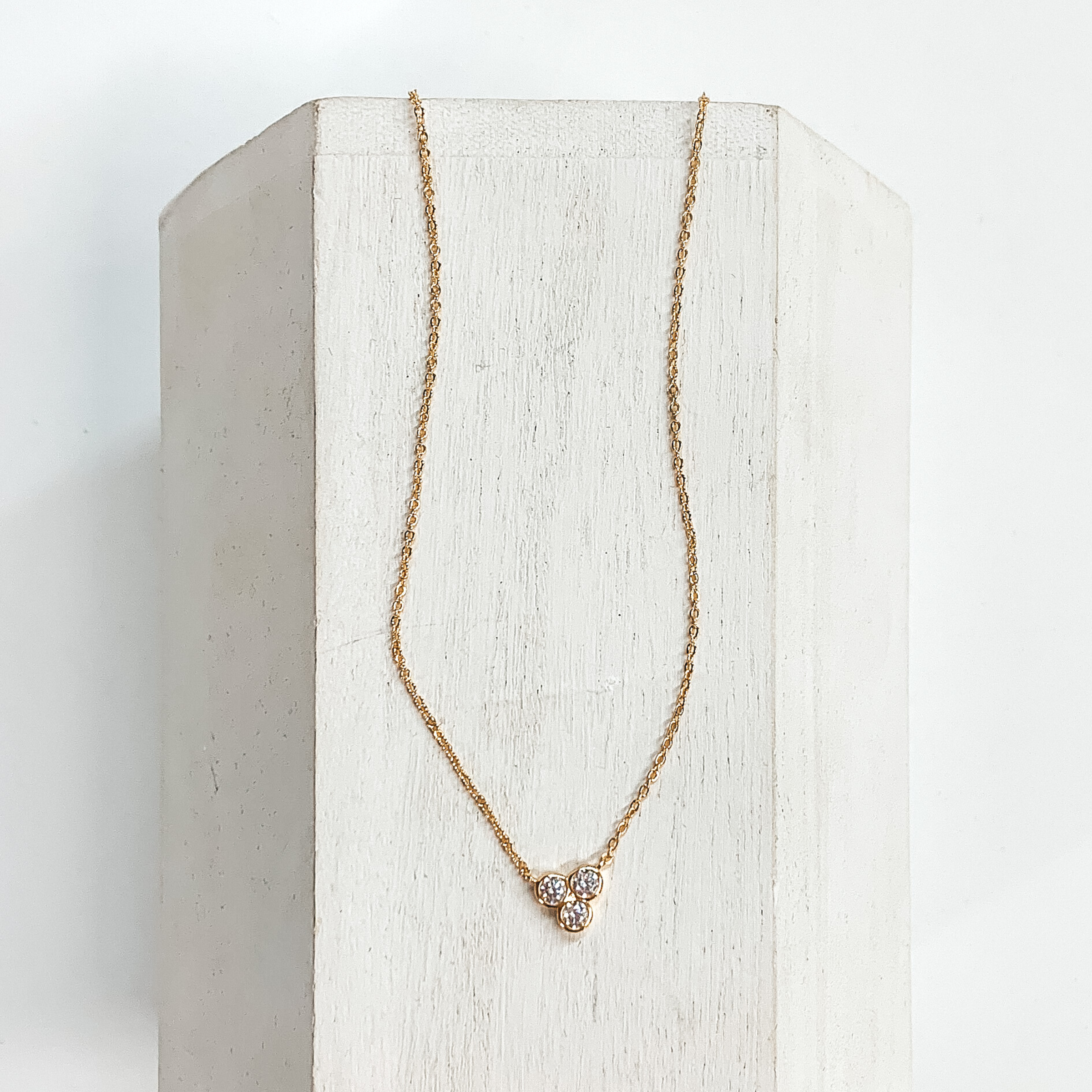 Thin gold chain necklace with CZ crystals in a cluster in the center. This  necklace is taken on a white block and a white background.
