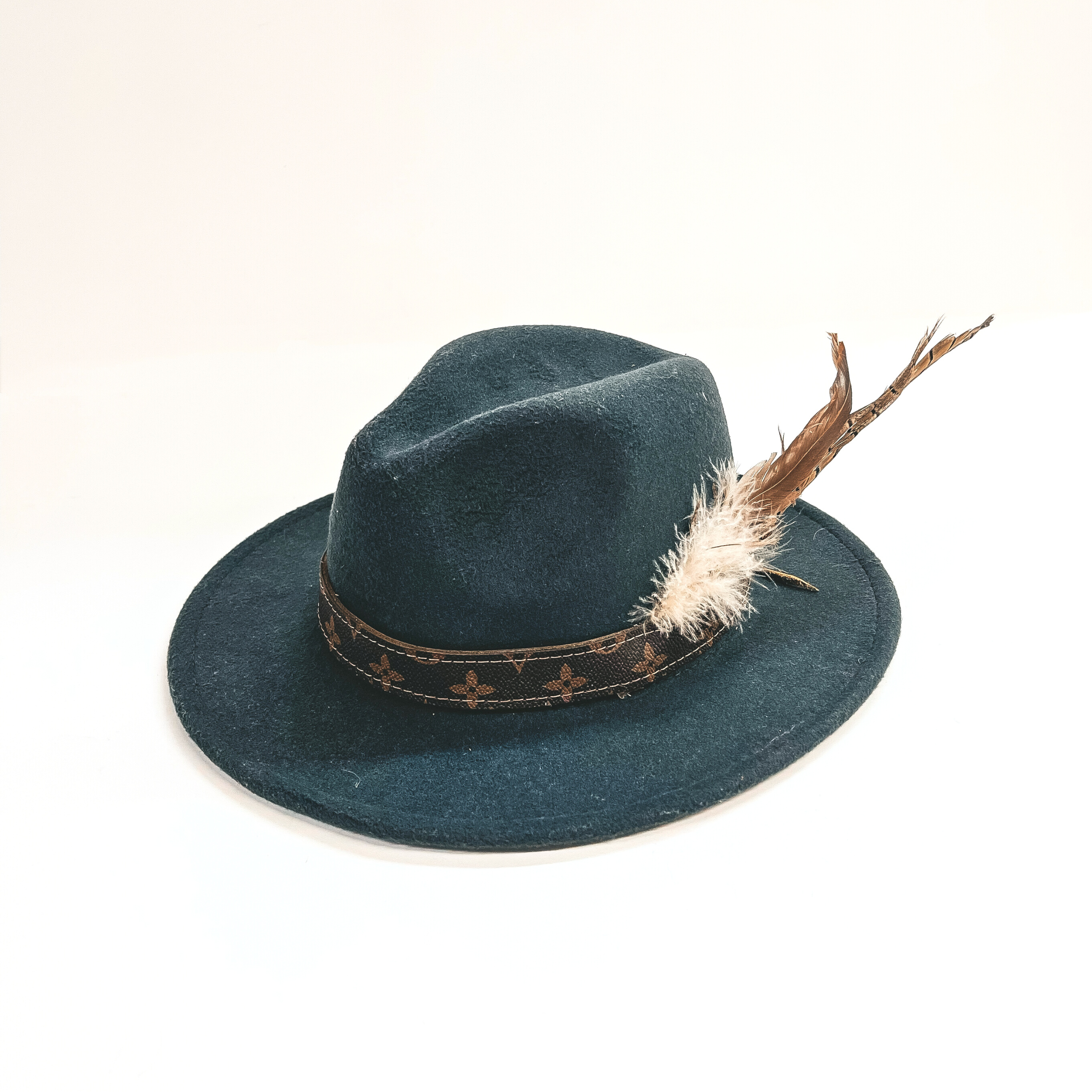 Charcoal gray fedora hat with a brown leather hand band and feathers in the side as accessories. This hat is taken on a white background.
