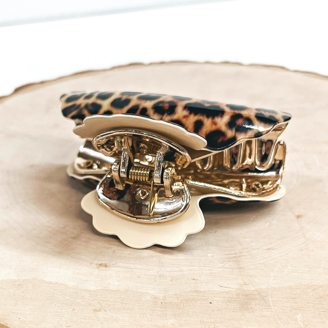This is a yellow leopard print hair clip with a gold tone inlay in ivory.   This hair clip is taken on a slab of wood and on a white background.