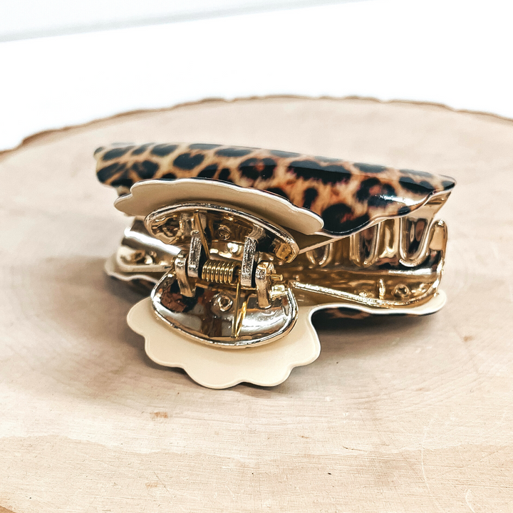 This is a yellow leopard print hair clip with a gold tone inlay in ivory.   This hair clip is taken on a slab of wood and on a white background.