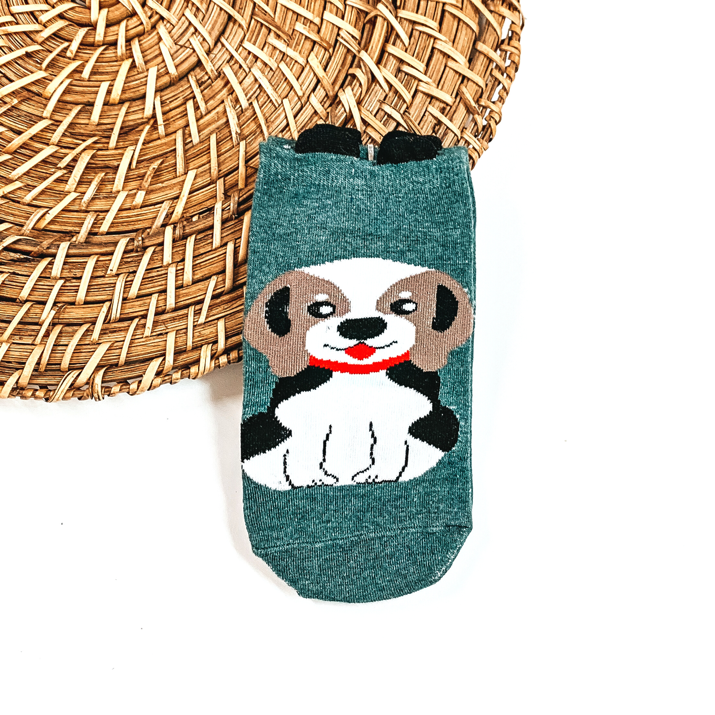 This is a dark green pair of socks with a brown/white Beagle and red collar. There  are small black ears on top on the socks.  This pair of socks are taken on a brown woven slate and on a white  background.