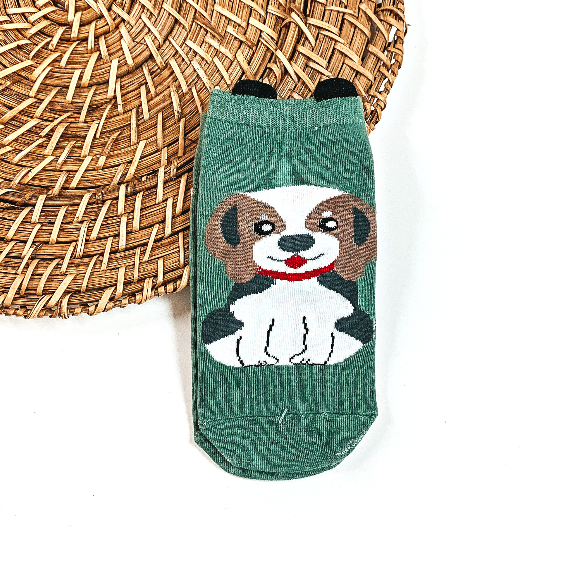 This is a green pair of socks with a brown/white Beagle and red collar. There  are small black ears on top on the socks.  This pair of socks are taken on a brown woven slate and on a white  background.