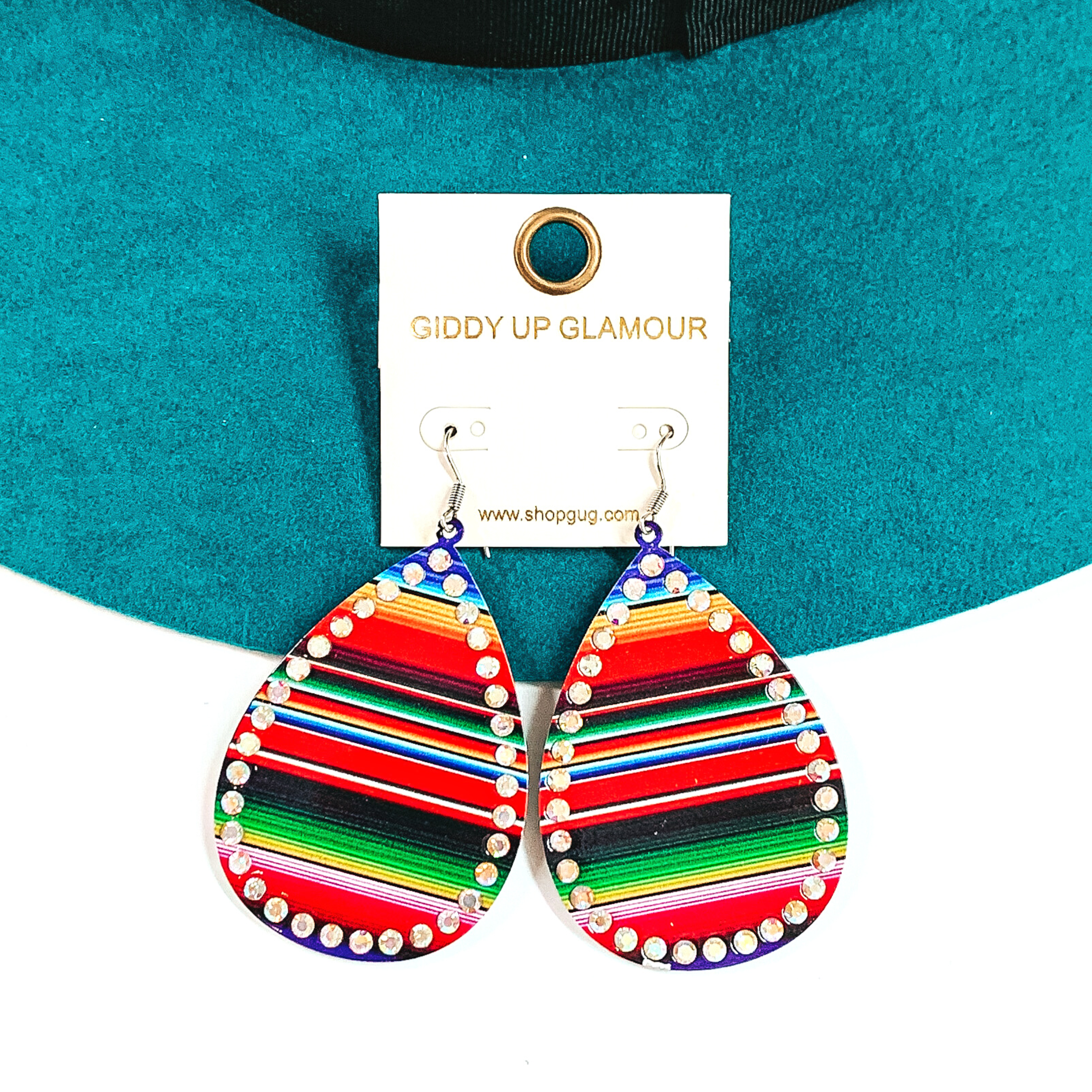 These are teardrop serape print earrings with ab crystals all around. The serape print  is in a red mix such as; red, blue, orange, green, and a bit of black. These  earrings are taken on a teal felt hat brim and on a white background.