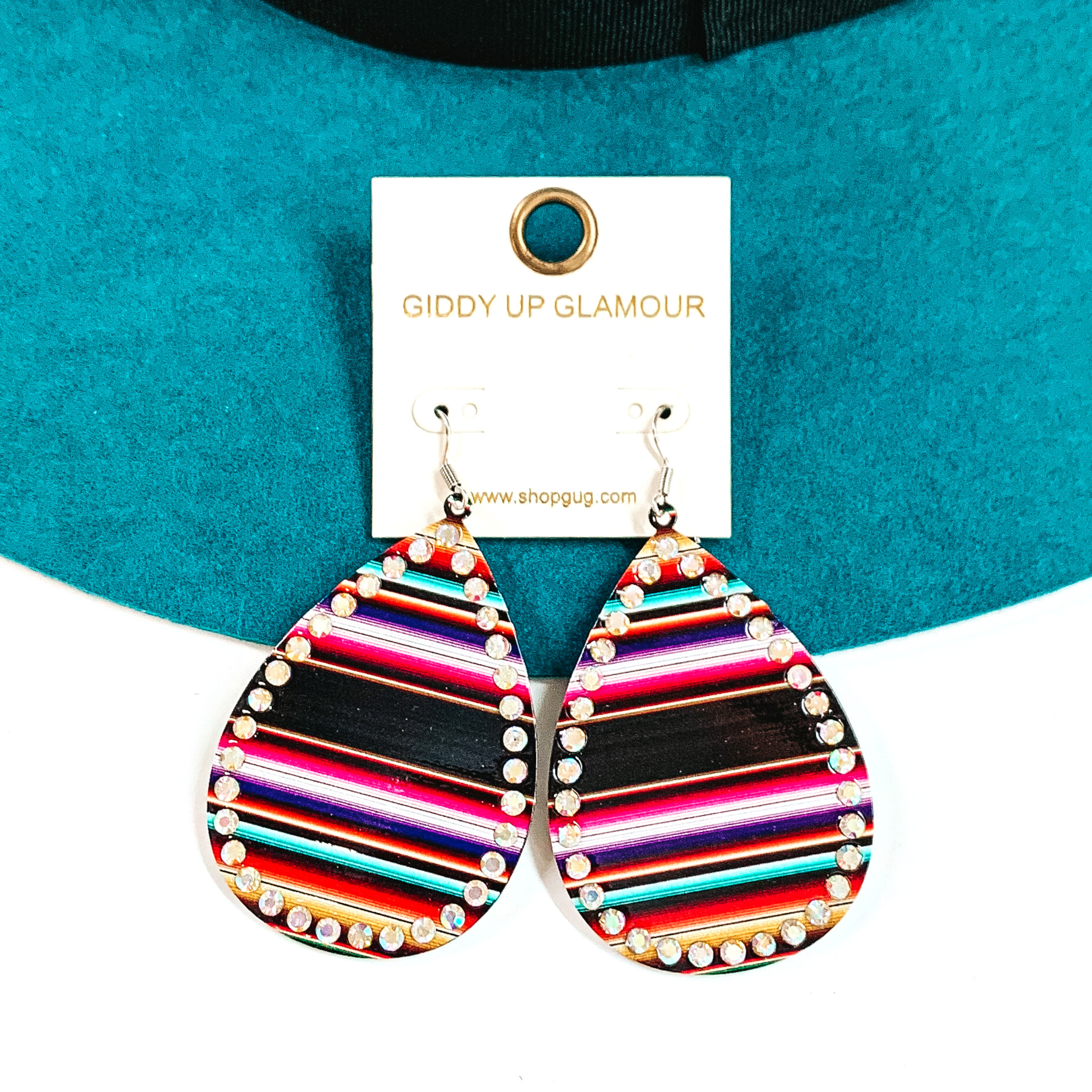 These are teardrop serape print earrings with ab crystals all around. The serape print  is in a black mix such as; black, purple, turquoise, pink, and a bit of red. These  earrings are taken on a teal felt hat brim and on a white background.