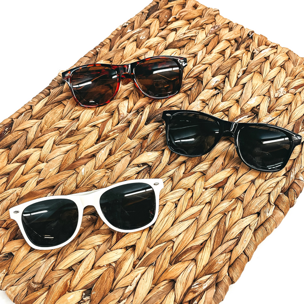 These are three pair of round sunglasses in various colors and prints such as  black, white, and tortouise print. These sunglasses are taken on a brown woven slate  and on a white background.