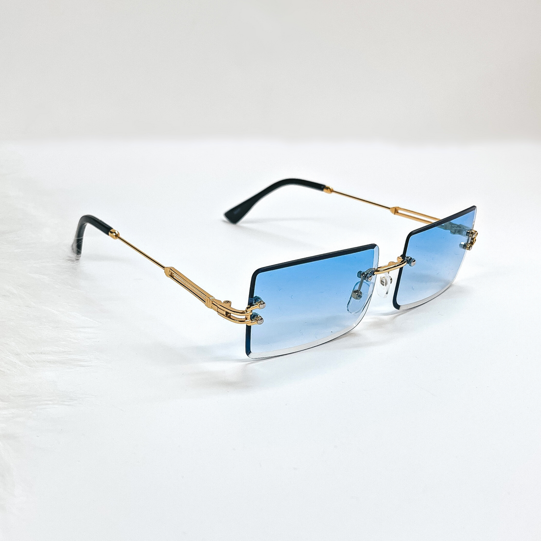 This is a blue pair of sunglasses, the lenses are blue with no frame and they have  gold connectors. The ear pieces are black. These sunglasses are taken  on a white background with a piece of white fur in the side as decor.