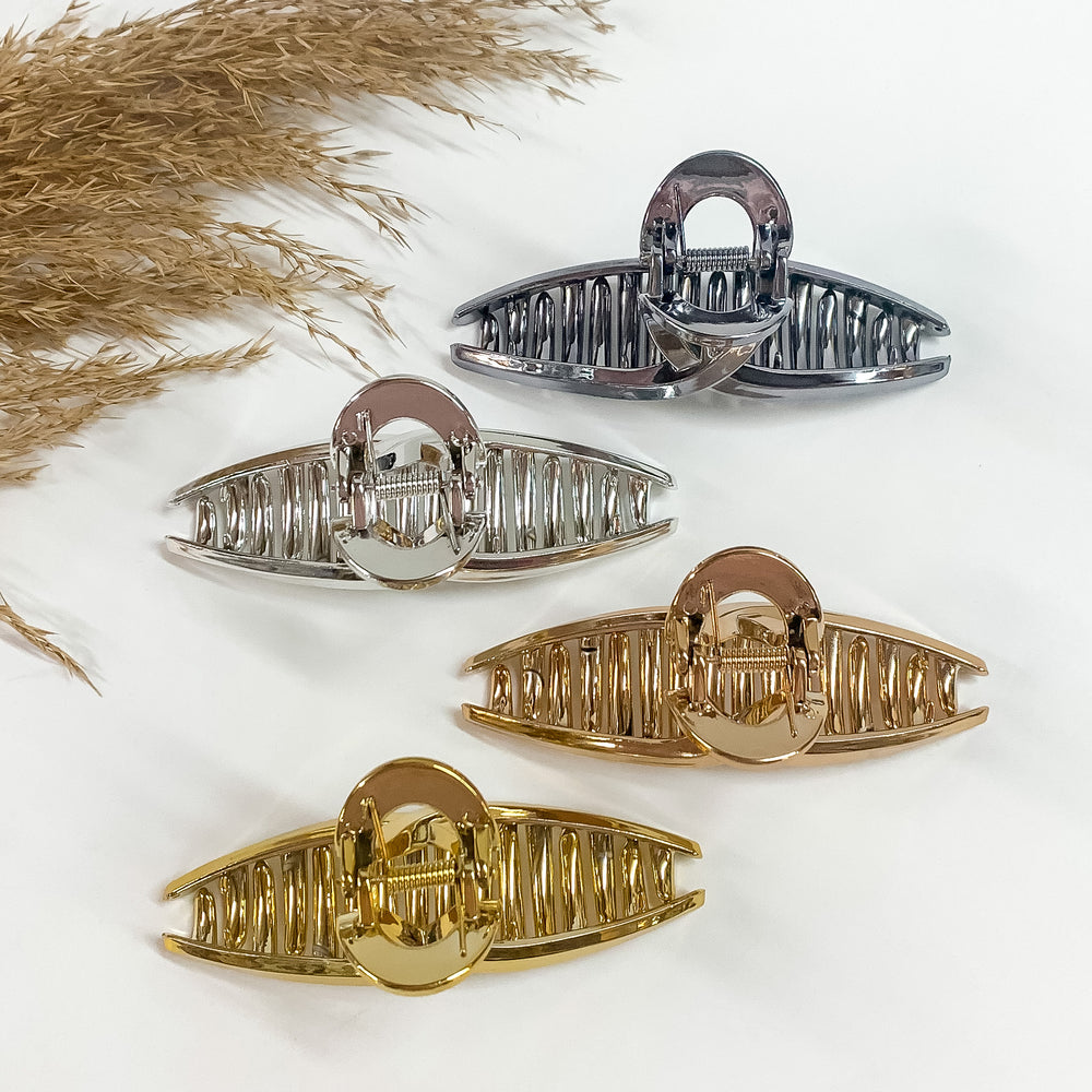 There are four loop clips in metallic laying on a white backround  with a brown plant in the side as decor. There is gunmetal, silver, copper,  and gold.