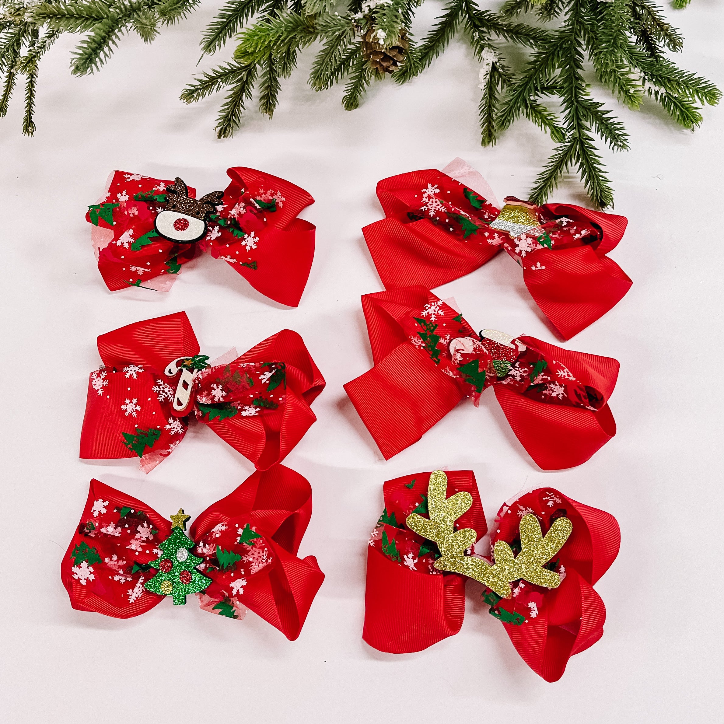 Pictured on a white background are six red bows. Each bow has a unique christmas charm in the center.