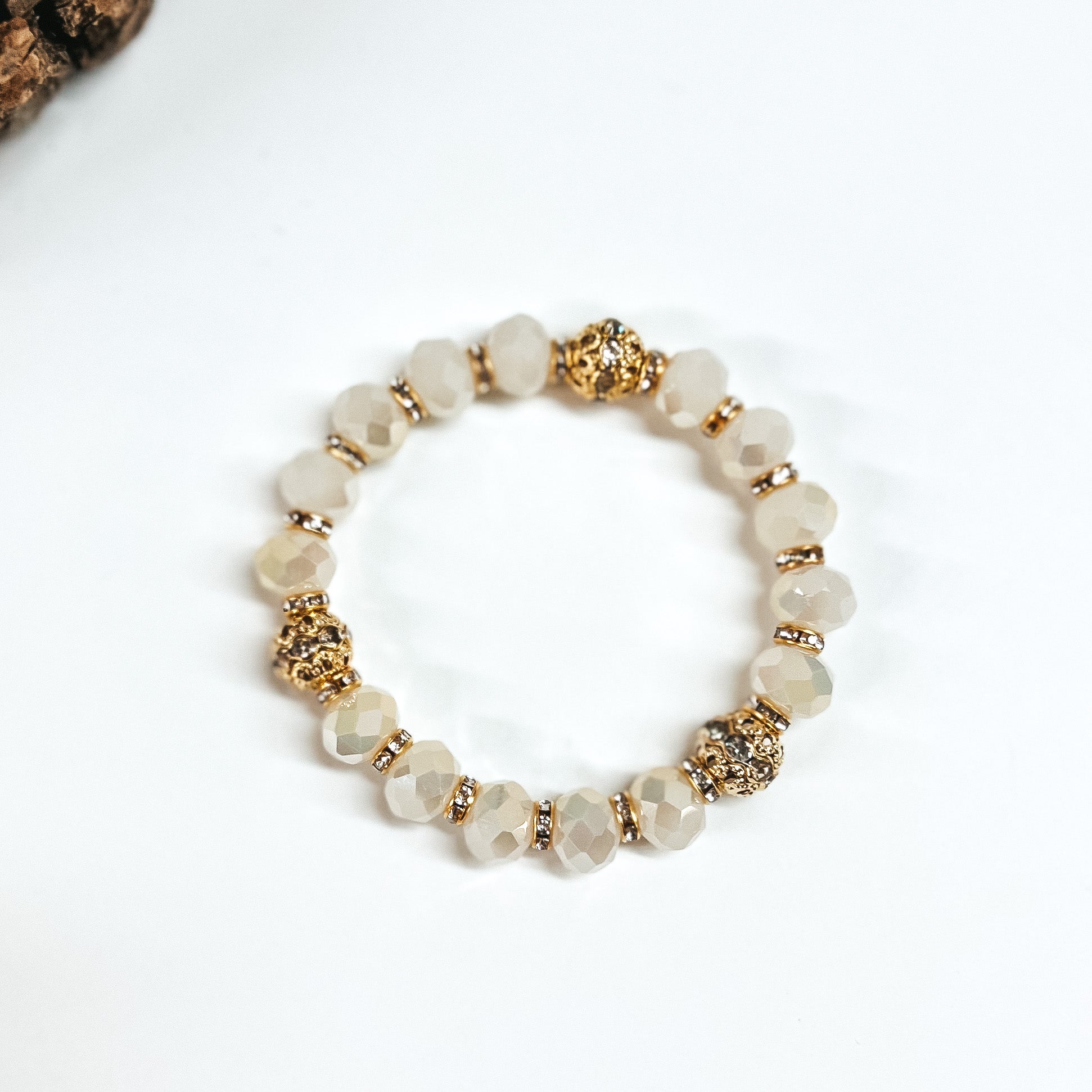 This is ivory crystal beaded bracelets with gold spacers. The gold spacers have clear crystals in them and there are three gold and crystals beads. This bracelet is taken on white background.