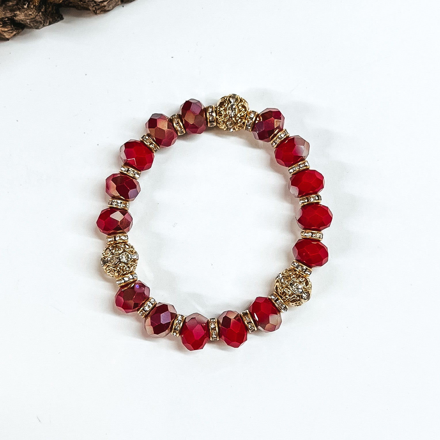 This is red/maroon mix crystal beaded bracelets with gold spacers.  The gold spacers have clear crystals in them and there are three gold and  crystals beads.This bracelet is taken on white background.