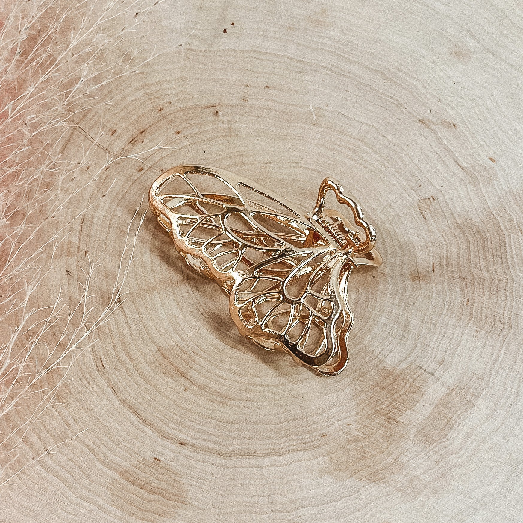 Gold butterfly hair clip pictured on a piece of wood. 