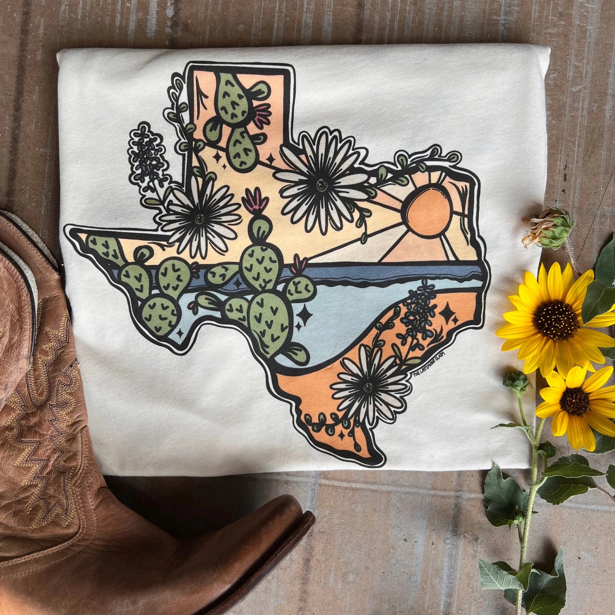 This Cream Bella + Canvas tee includes a crew neckline, short sleeves, and a hand drawn Texas scene inside the outline of Texas. 