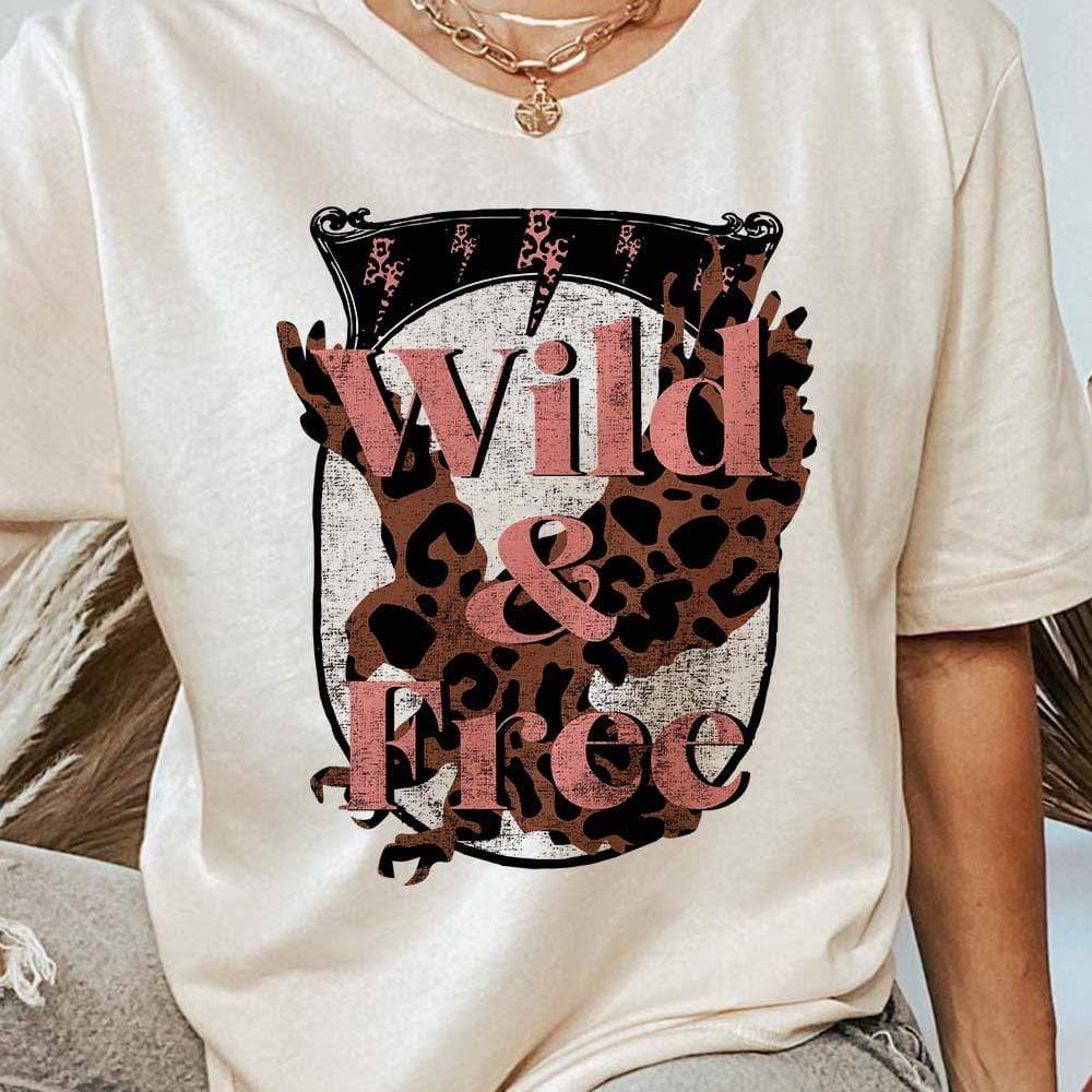 Model is wearing a cream colored graphic tee that has a leopard print eagle with the words "Wild & Free" written across.