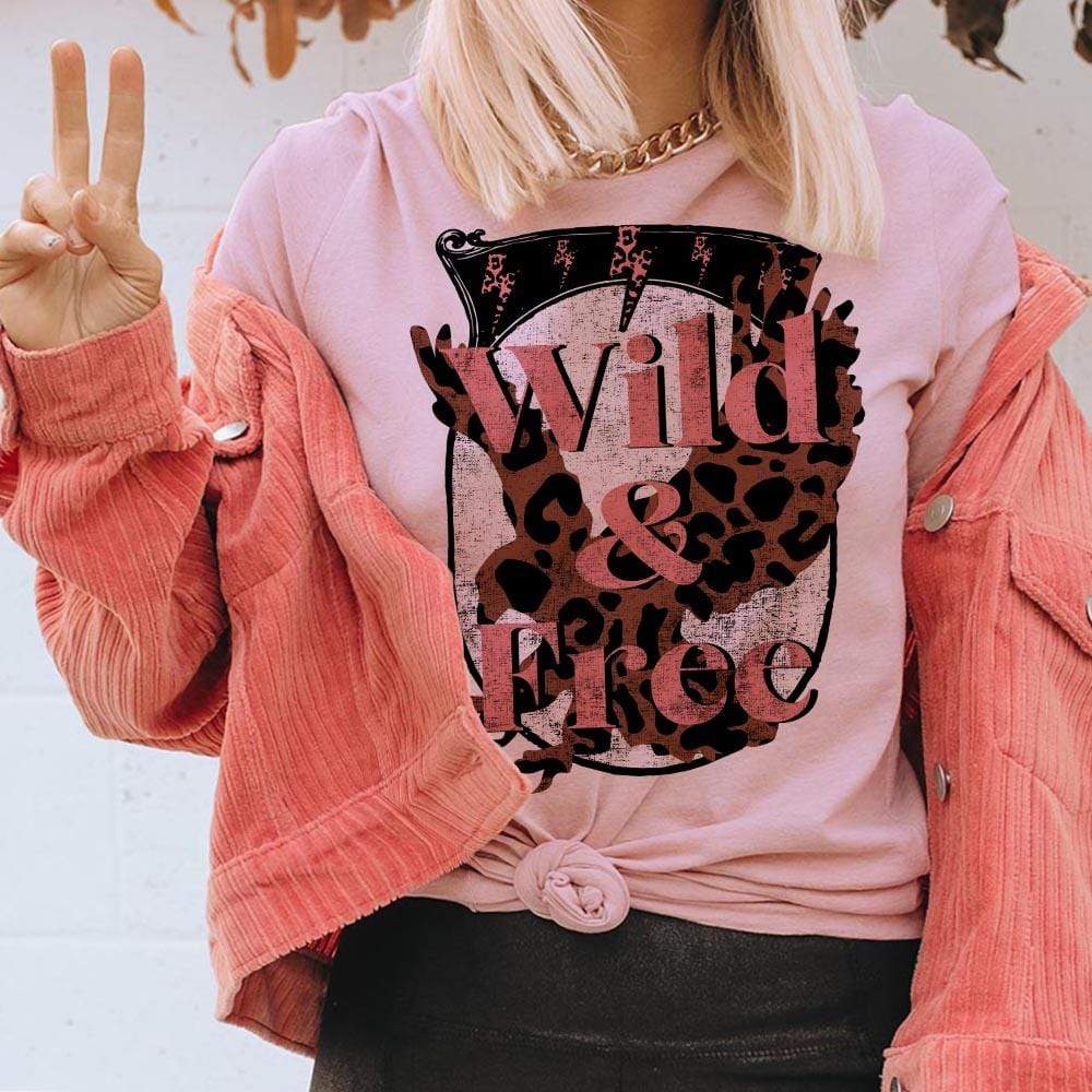 Model is wearing a rose pink colored graphic tee that has a leopard print eagle with the words "Wild & Free" written across.